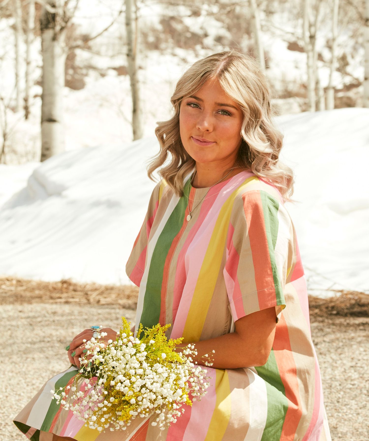 A springtime portrait featuring a striped pastel dress and small white wildflowers.