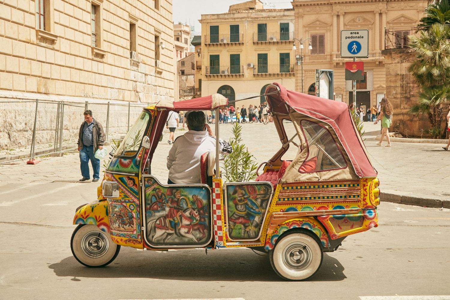 Colorfully decorated tuk-tuk taxi parked in a historic Mediterranean square.