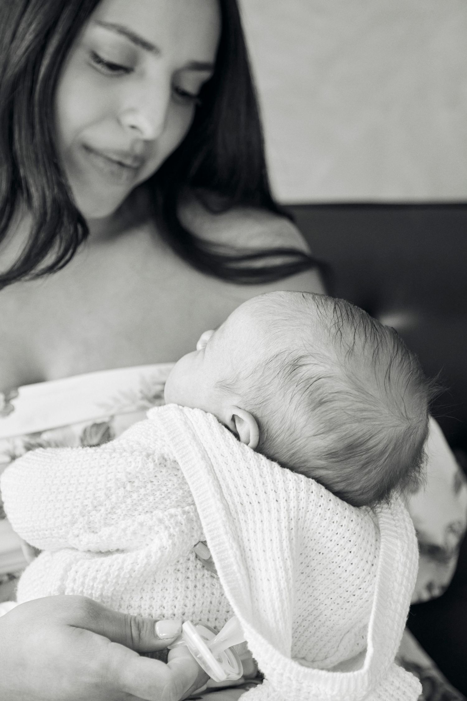 Black and white portrait of mother and sleeping newborn in soft, natural light.
