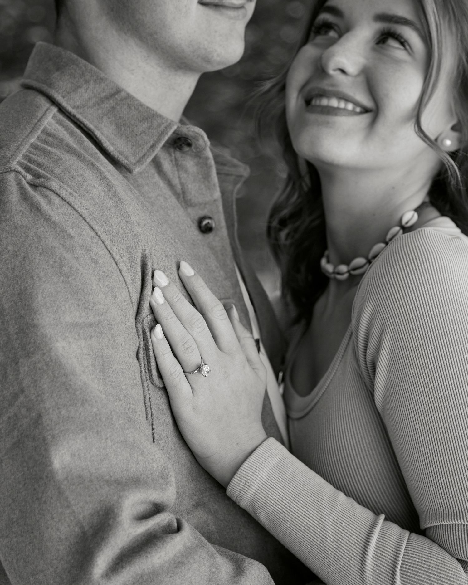 Close up of couple embracing showing engagement ring in black and white photography.