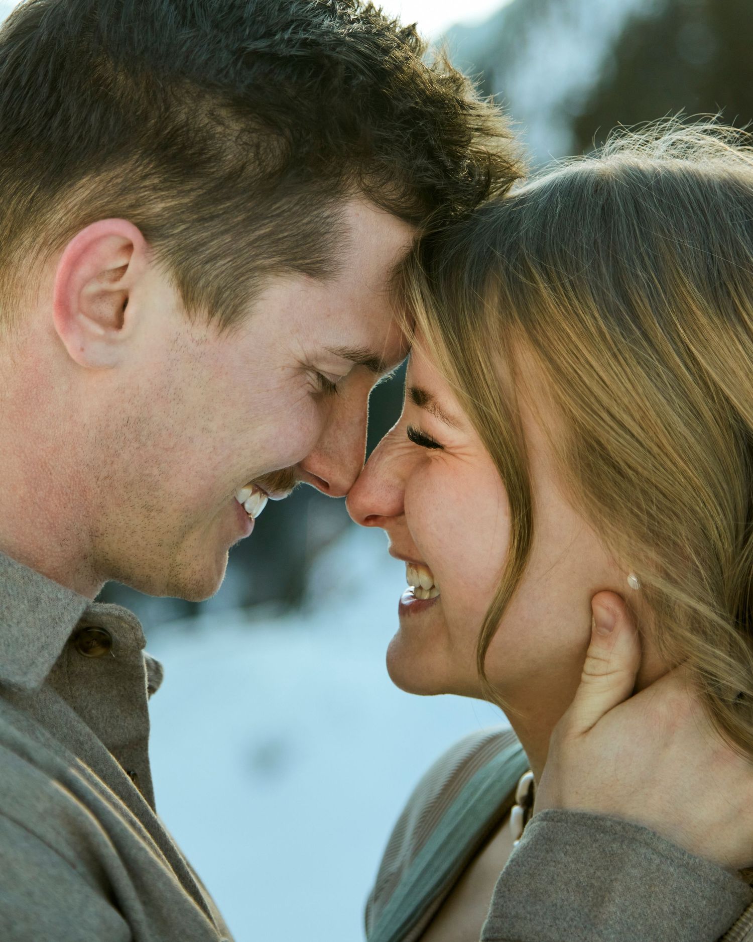 Close-up portrait showing tender affection against a snowy winter backdrop.