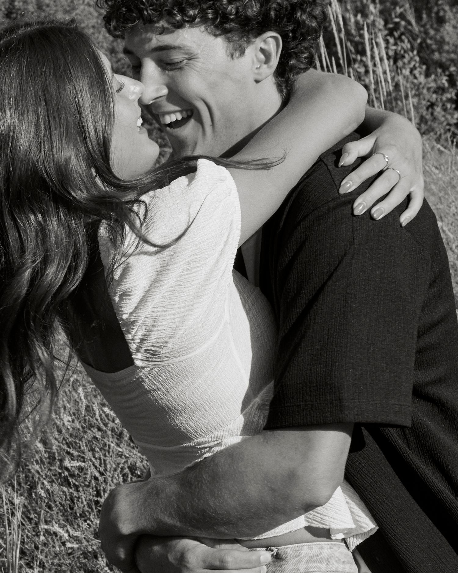 Black and white portrait of couple sharing intimate moment outdoors.