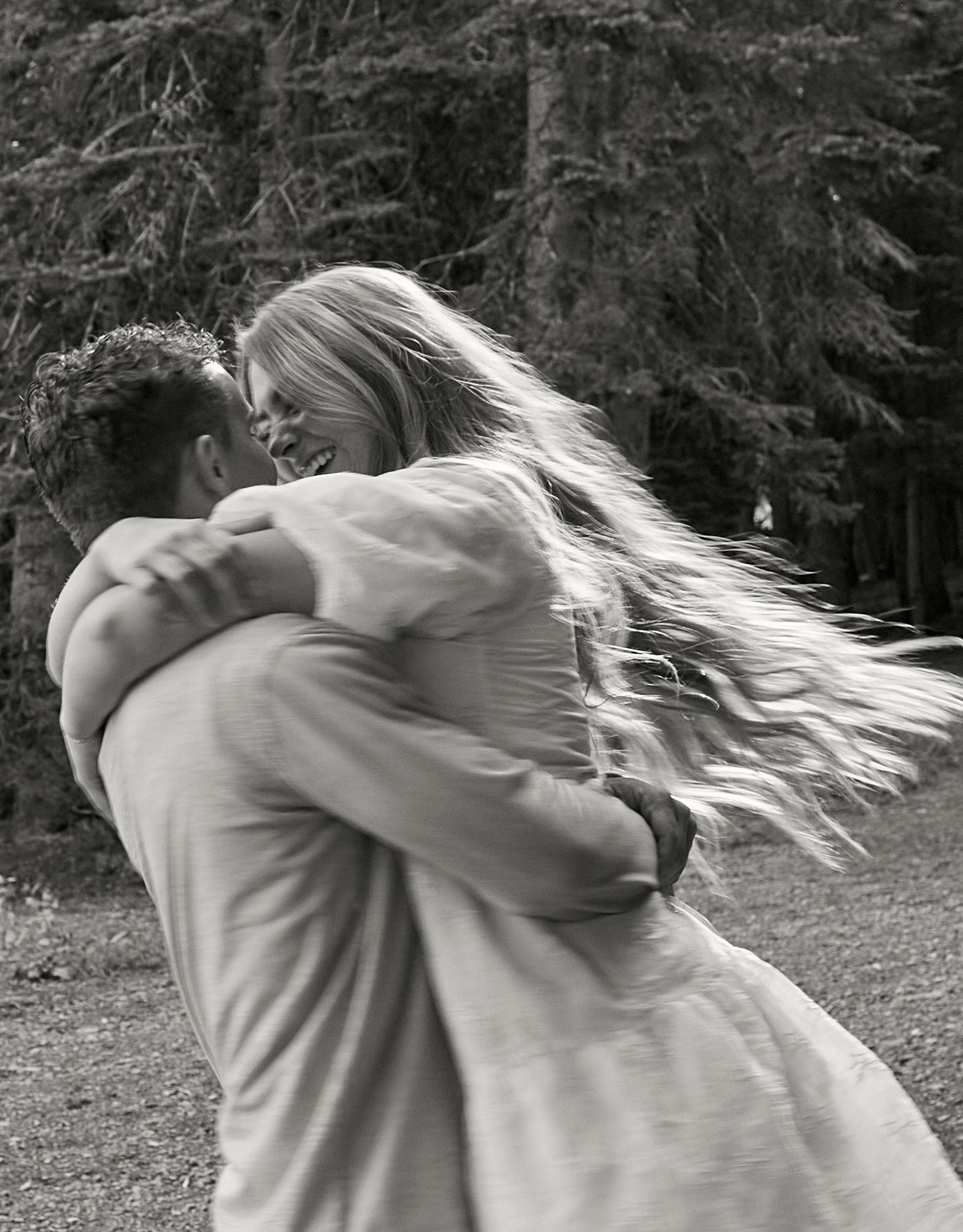 A romantic embrace captured in black and white with flowing hair caught in the wind.