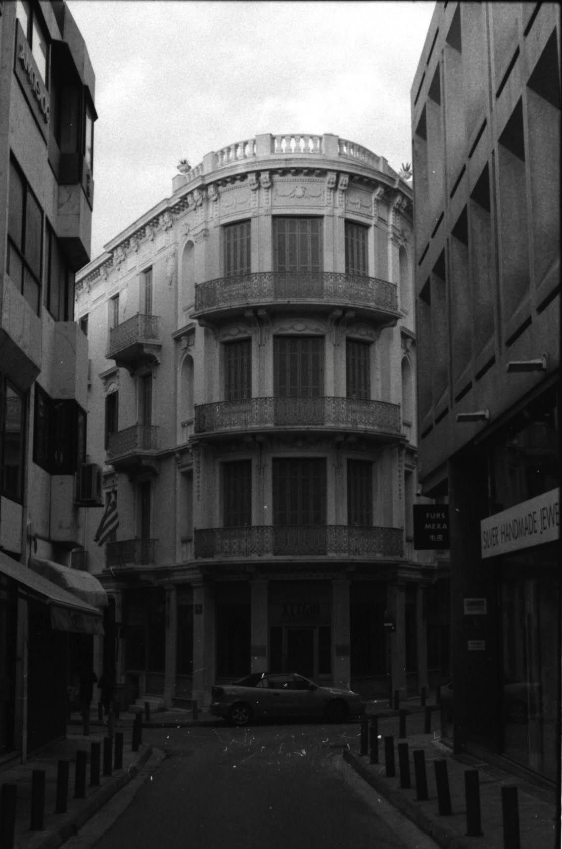 Historic curved corner building with ornate balconies and classical architecture in black and white.