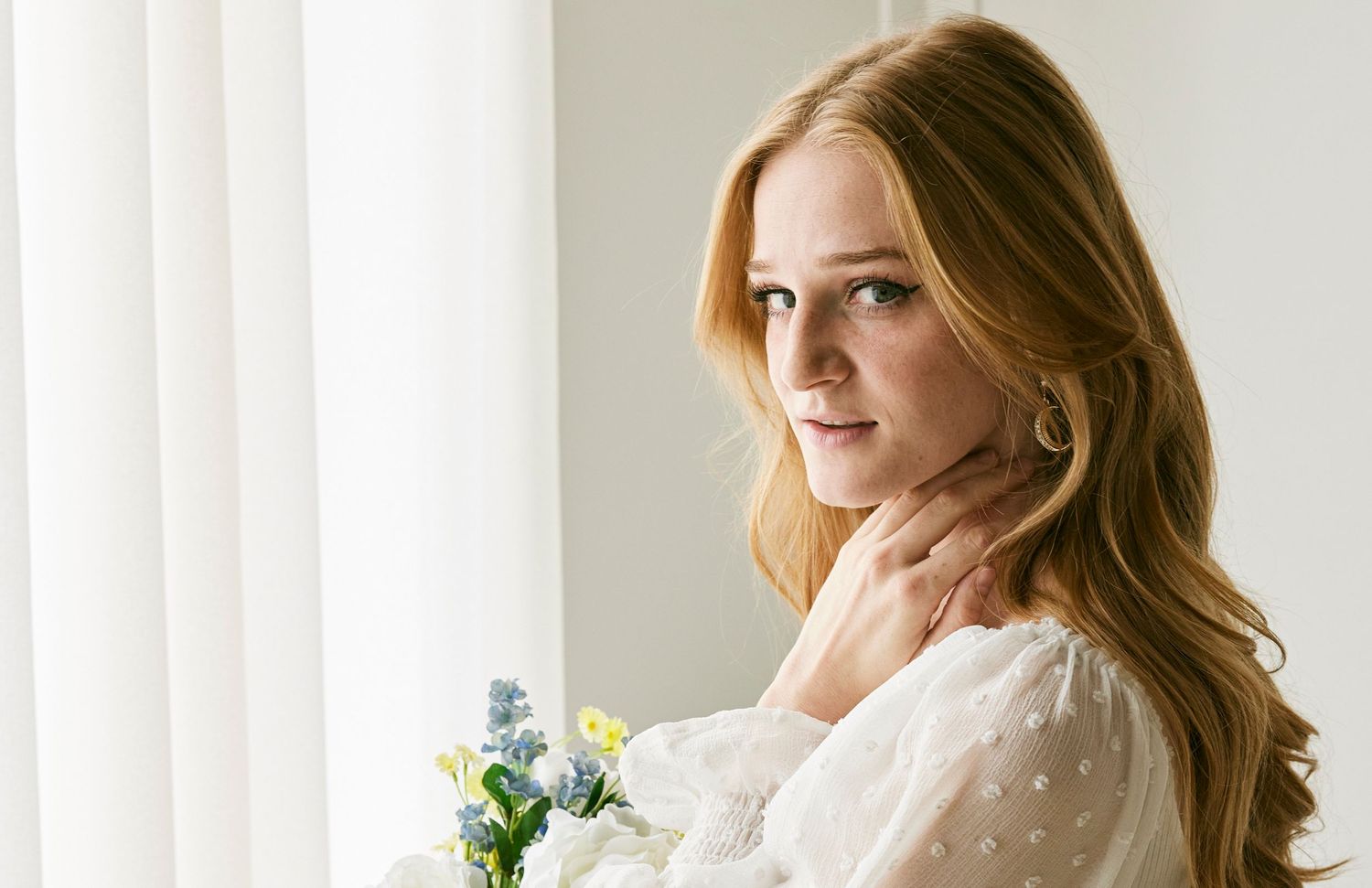 Soft portrait by window with white flowers and delicate dotted dress.