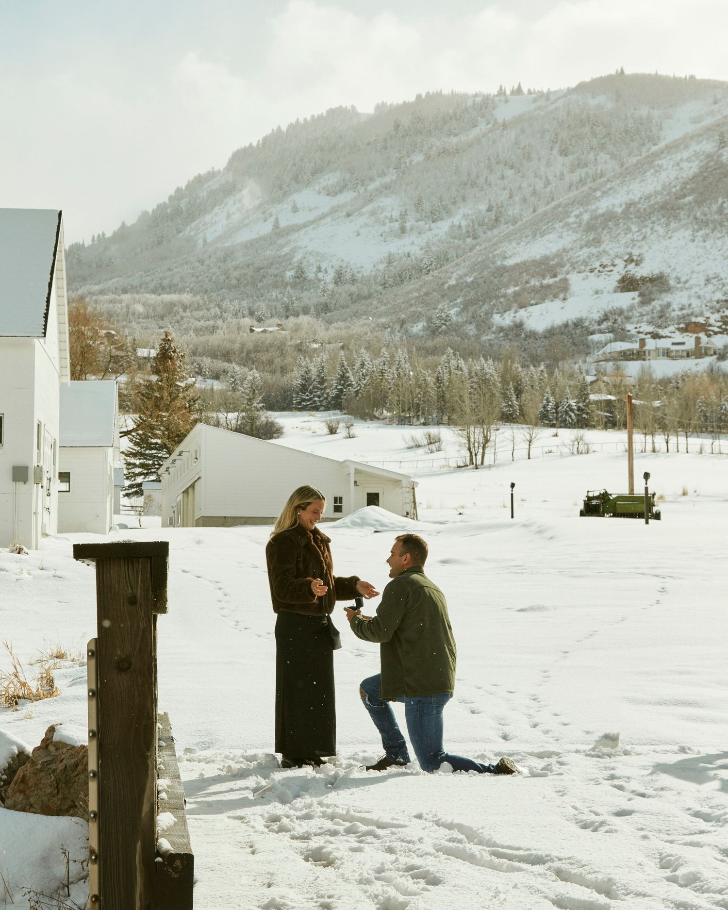 A proposal scene unfolds against a backdrop of snowy mountains and white buildings.