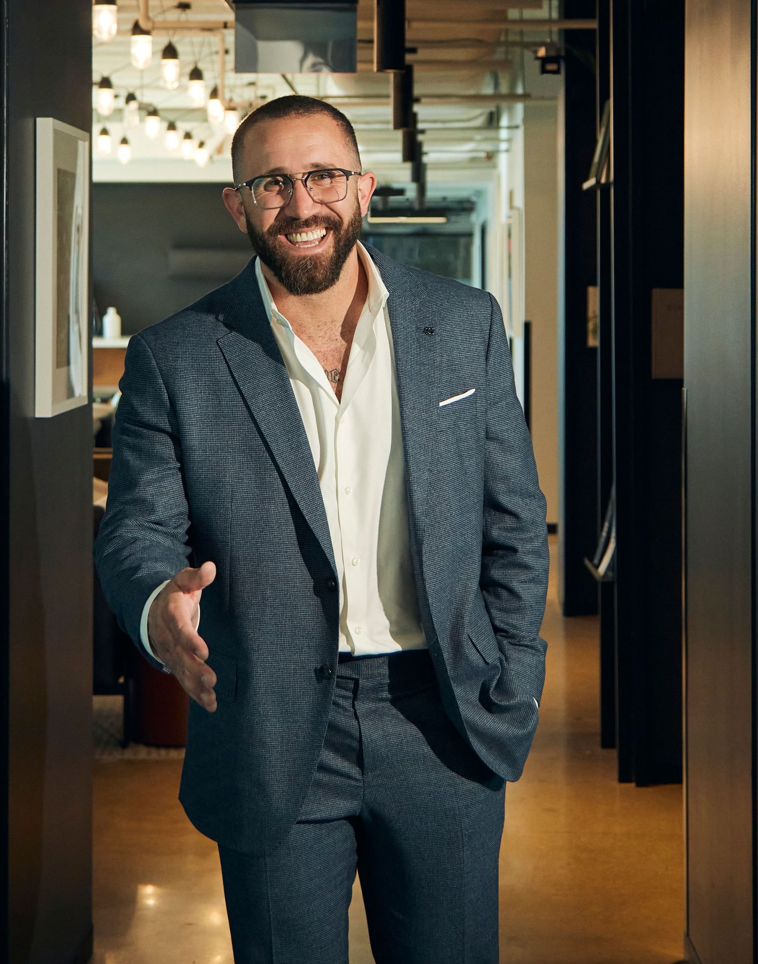 Welcoming businessman in modern office space with warm lighting.