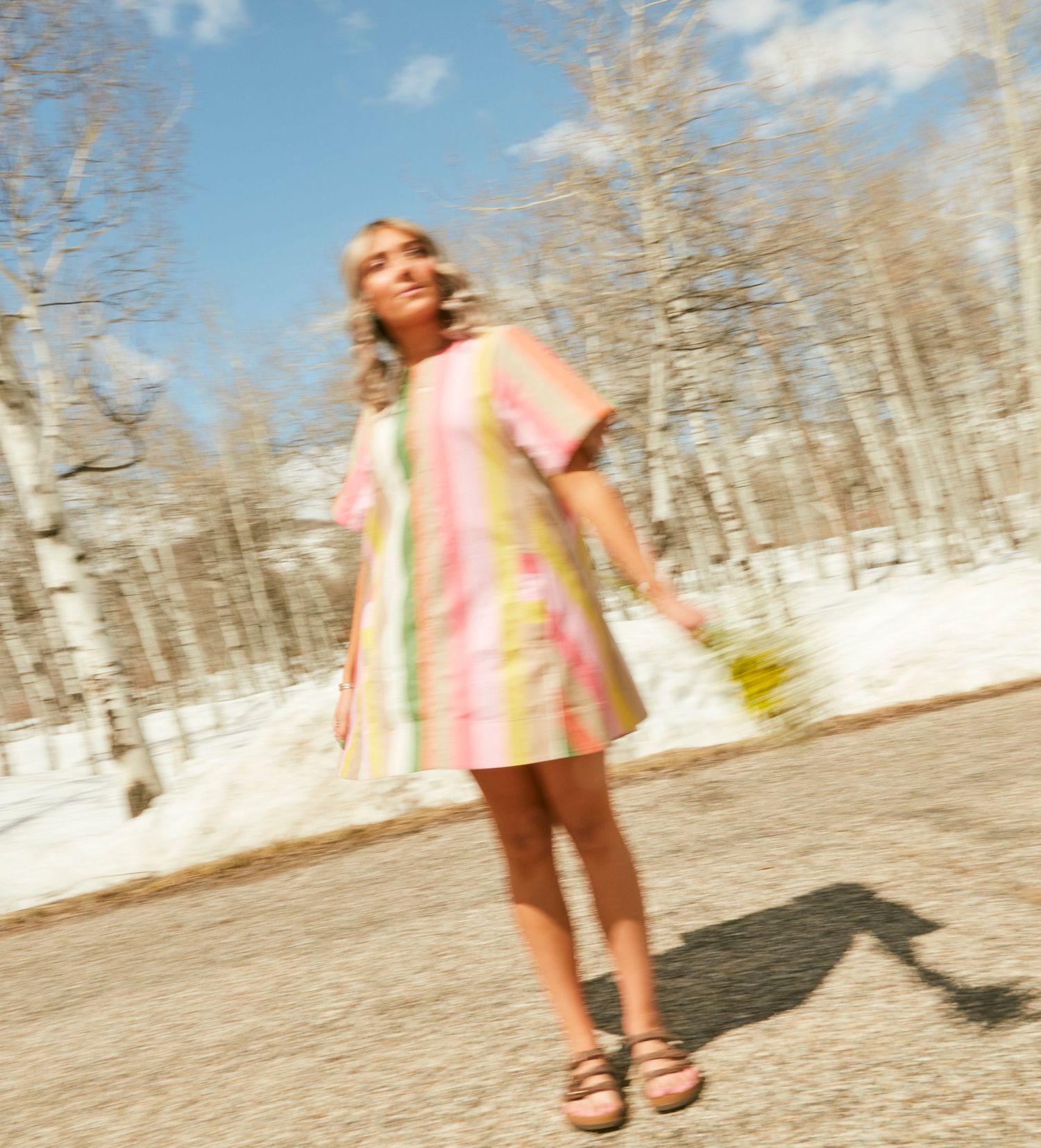 Motion-blurred photo of someone in a pastel striped dress against snowy background.