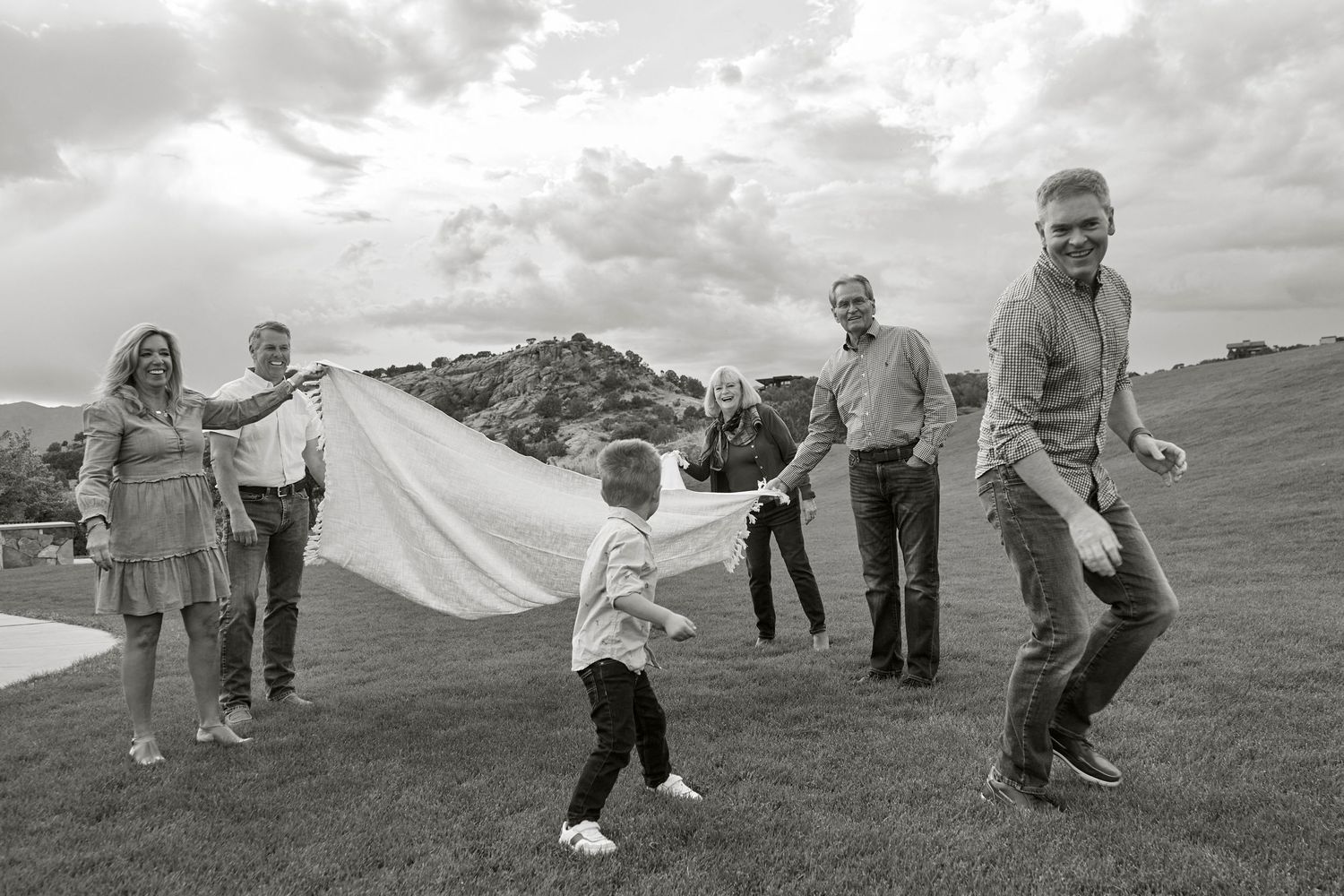 Black and white photo of people playing with a white sheet outdoors.
