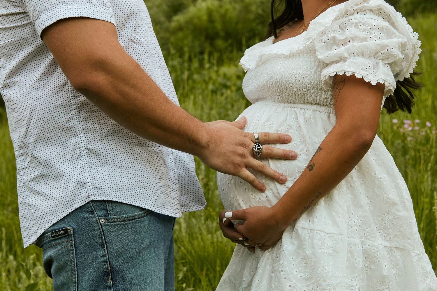 Close up detail shot of couple's hands embracing against white lace dress and casual shirt.