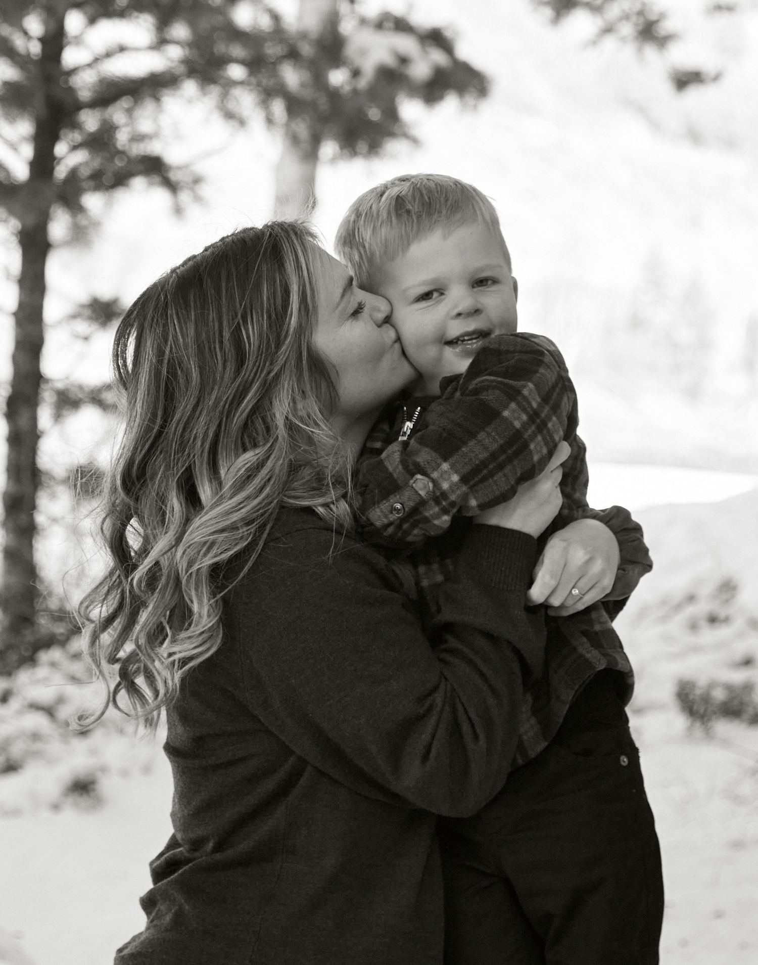 Tender black and white portrait of mother and child sharing an affectionate moment outdoors.