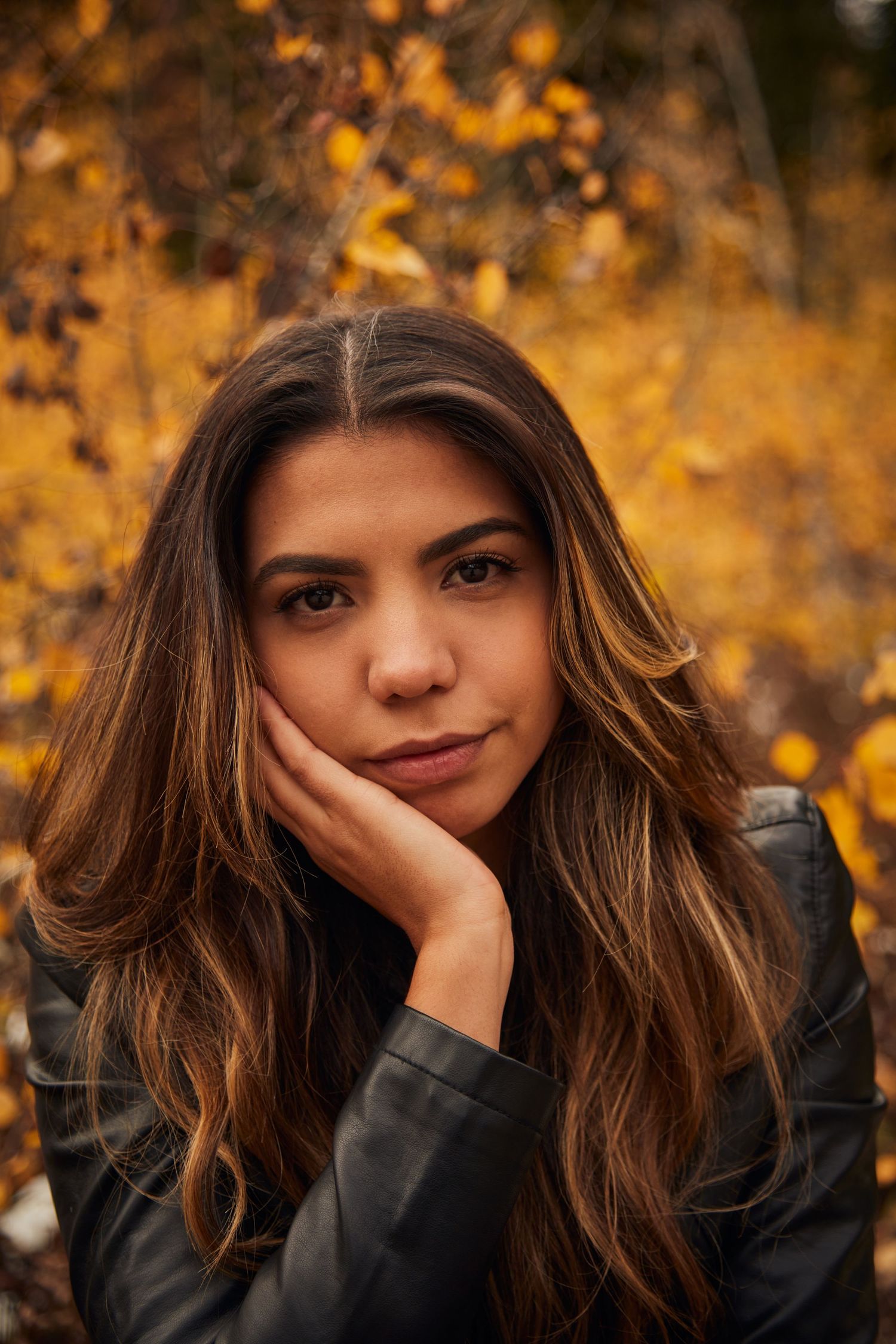 Autumn portrait with golden foliage background and casual leather jacket styling.