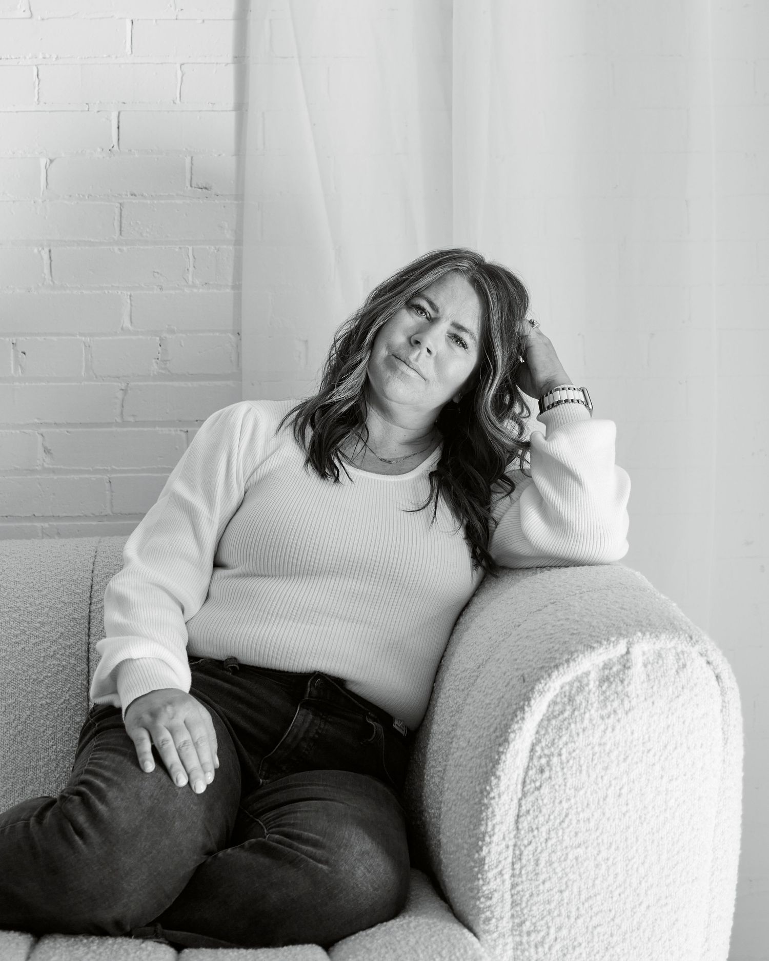A relaxed lifestyle portrait in black and white showing someone lounging on a plush armchair.