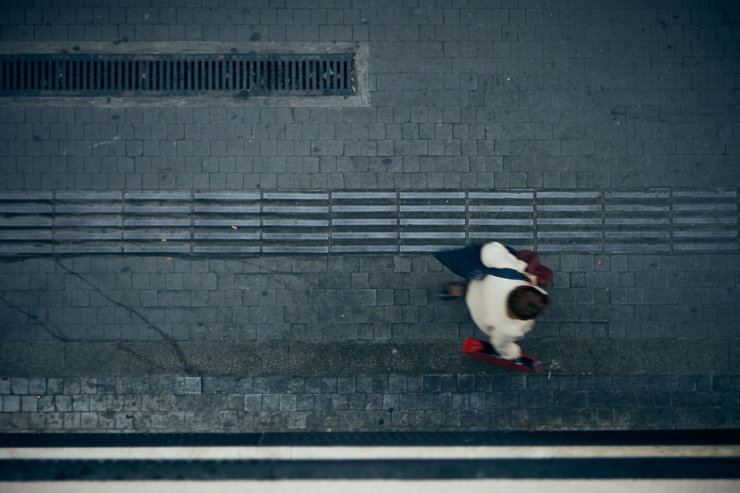Person in white standing alone against a grey industrial wall.