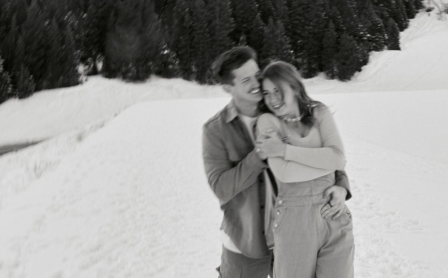 A romantic winter moment captured in black and white against a snowy mountain backdrop.