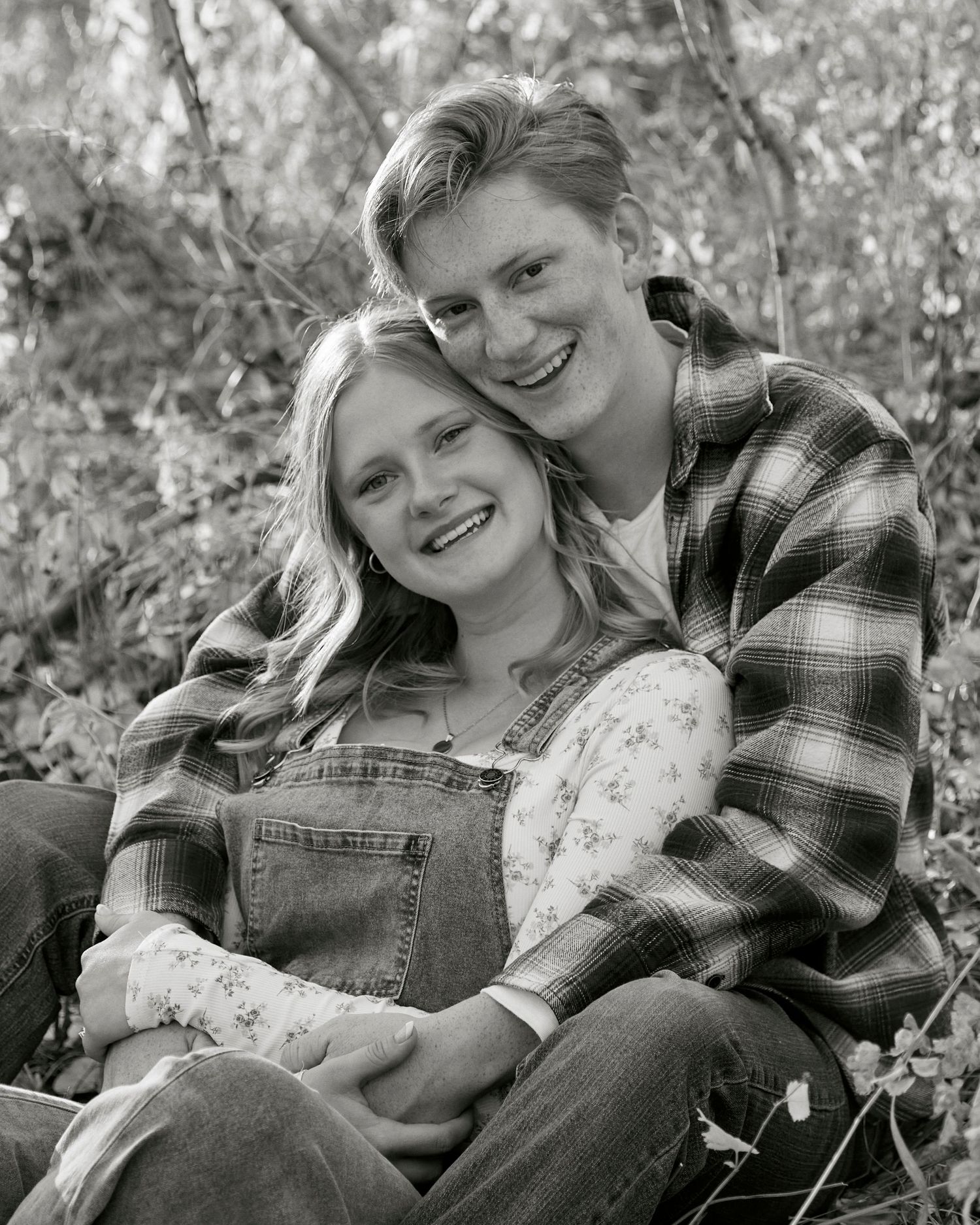 Black and white portrait of couple in casual wear sharing an intimate moment outdoors.