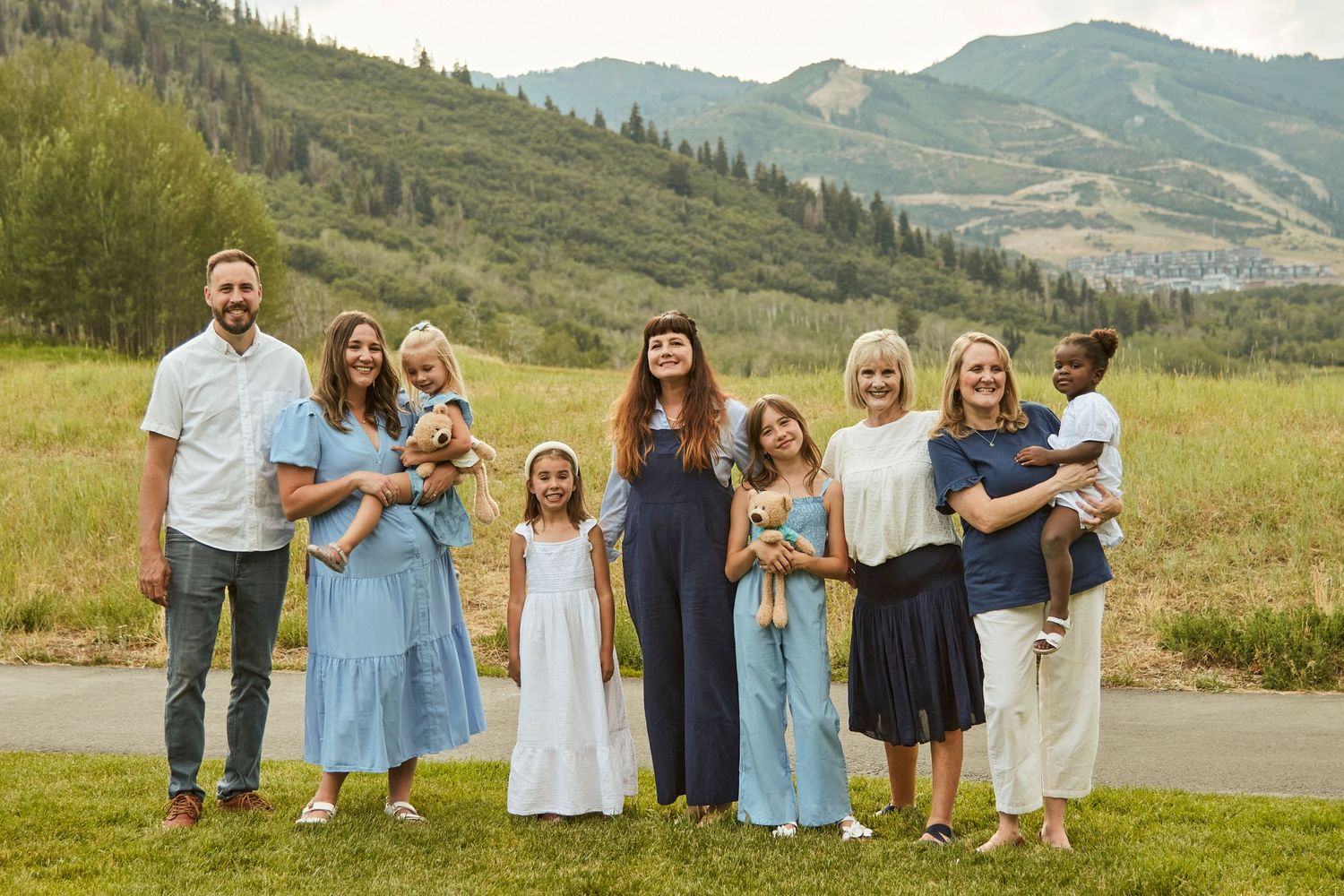 Large family group posed together outdoors with mountain landscape in background.