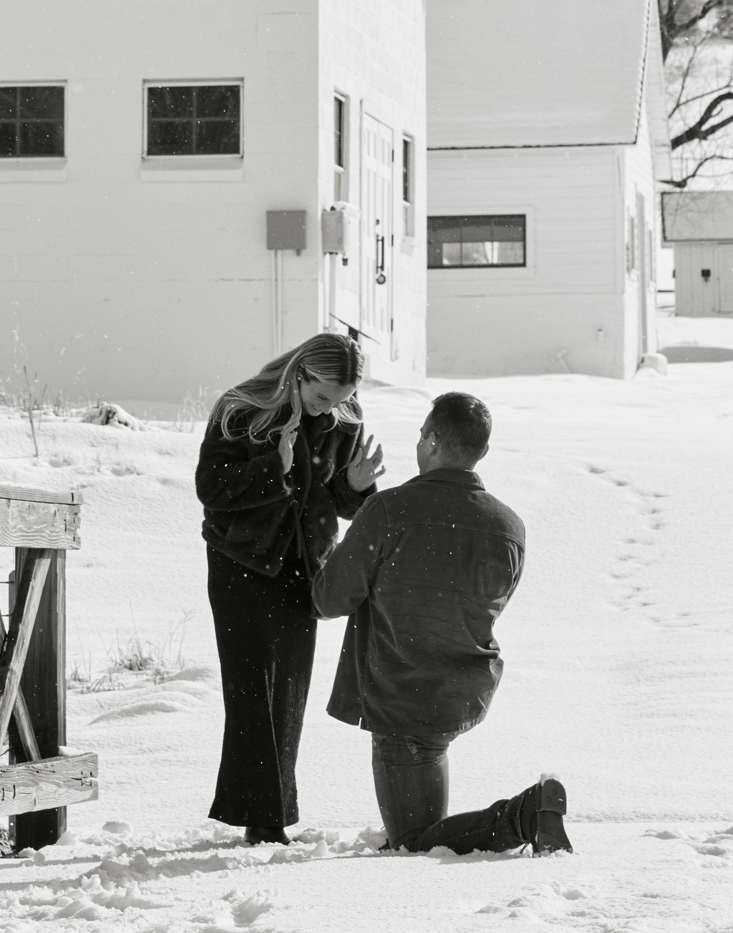 A special moment captured in black and white between two people against snow-covered buildings.