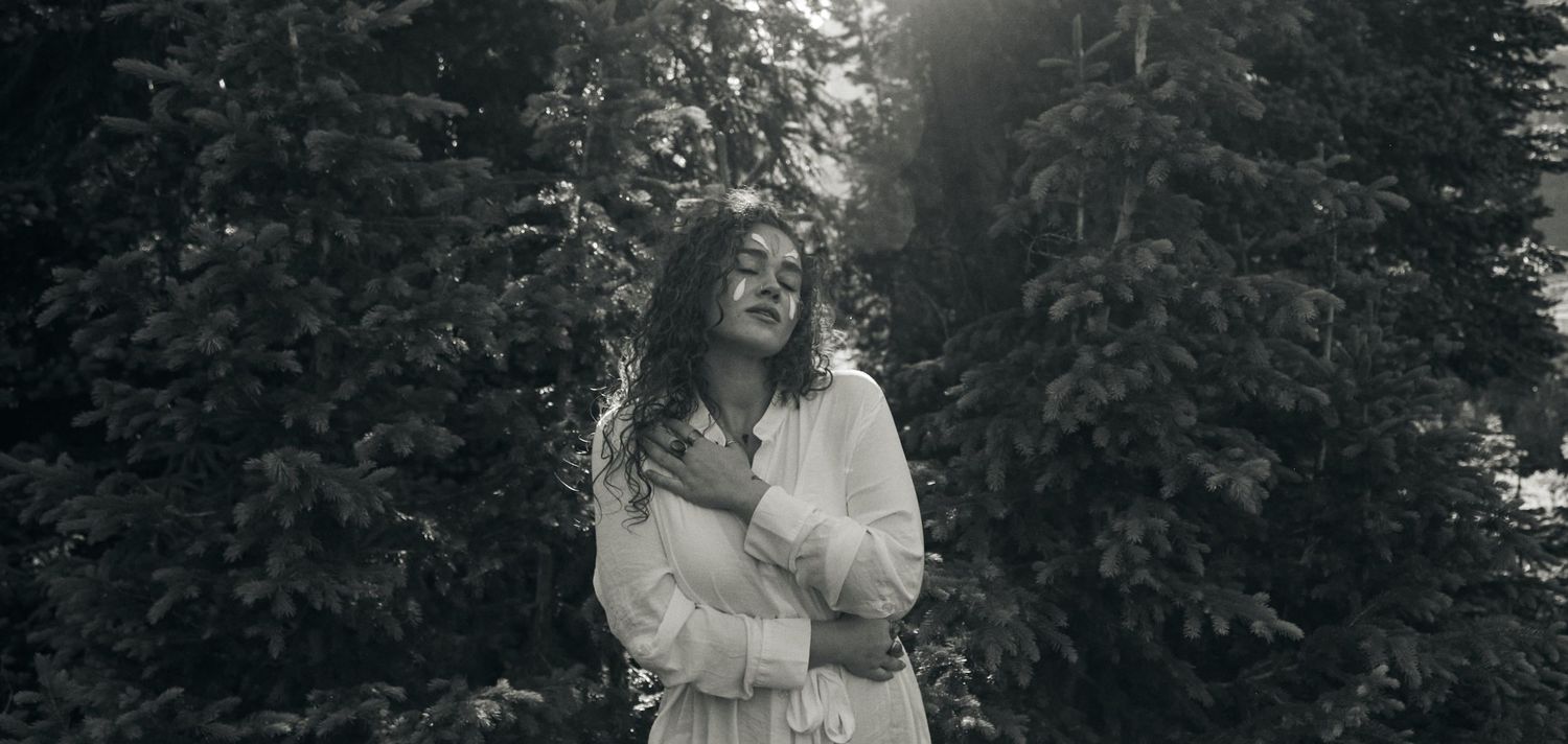 Black and white portrait amidst natural greenery and soft lighting.
