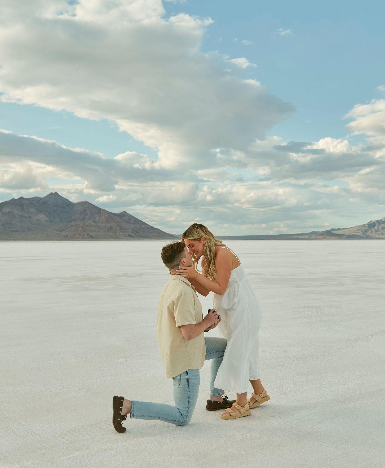 A couple sharing their first kiss after getting engaged on scenic salt flats.