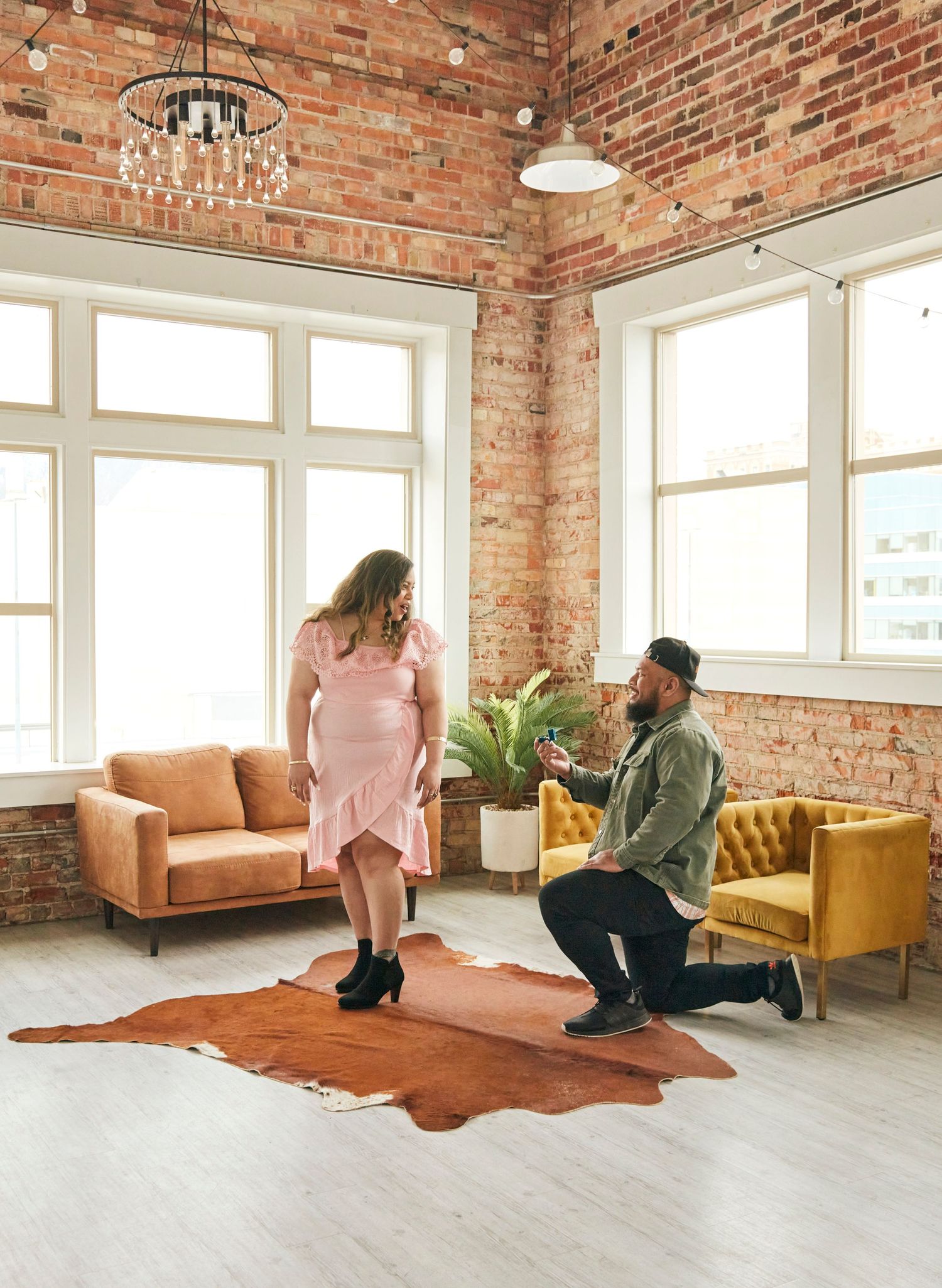 A proposal moment in a modern loft space with exposed brick walls and a cowhide rug.