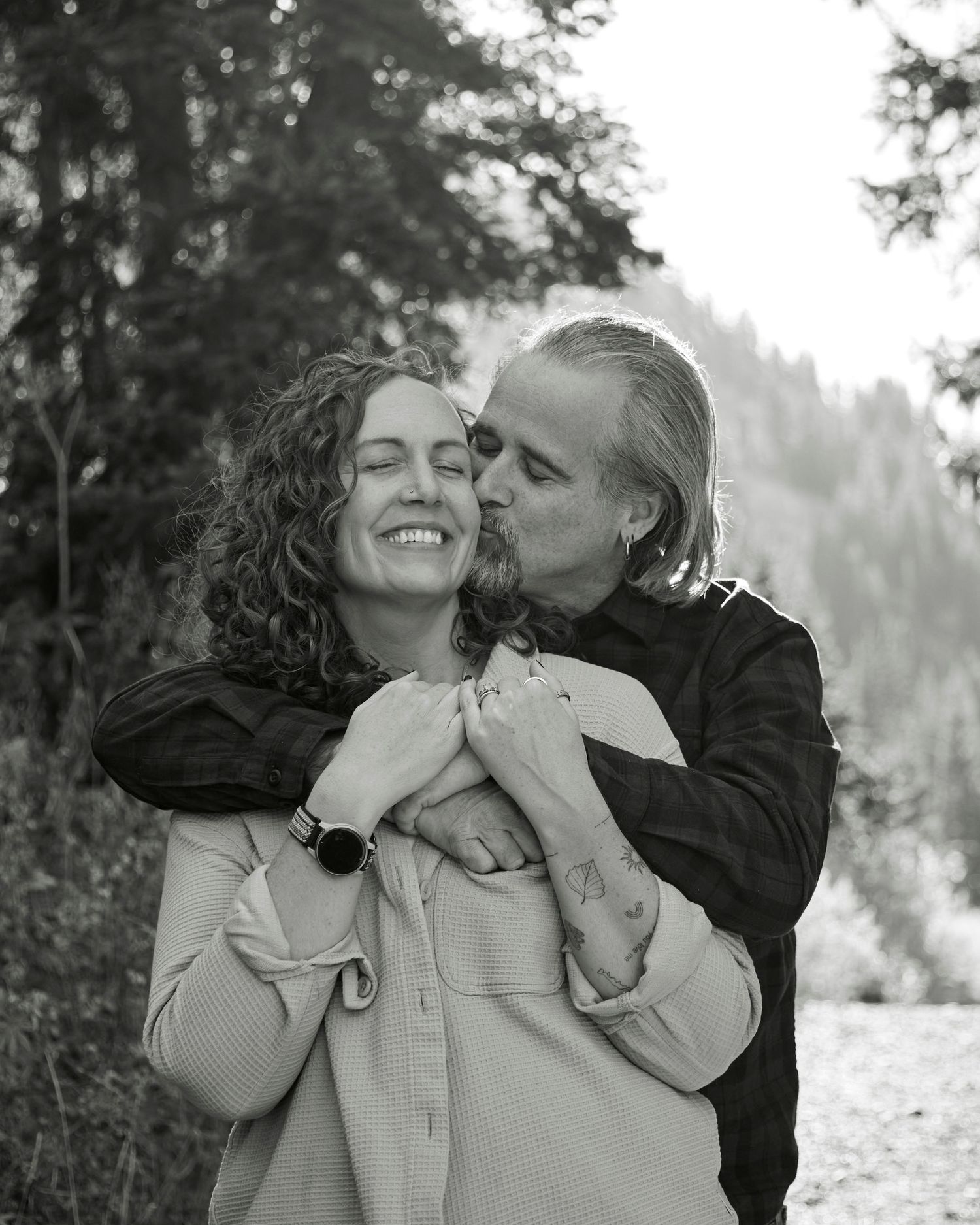 Intimate black and white portrait of couple embracing outdoors in natural setting.