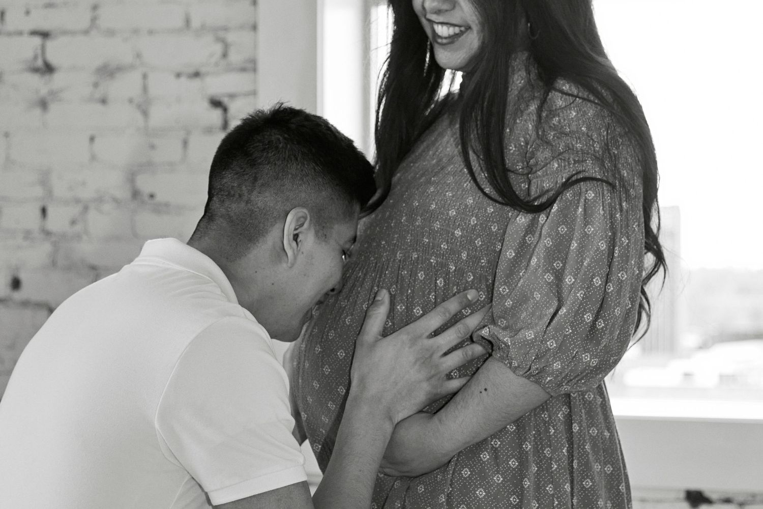 A touching maternity moment captured in a bright industrial-style room.