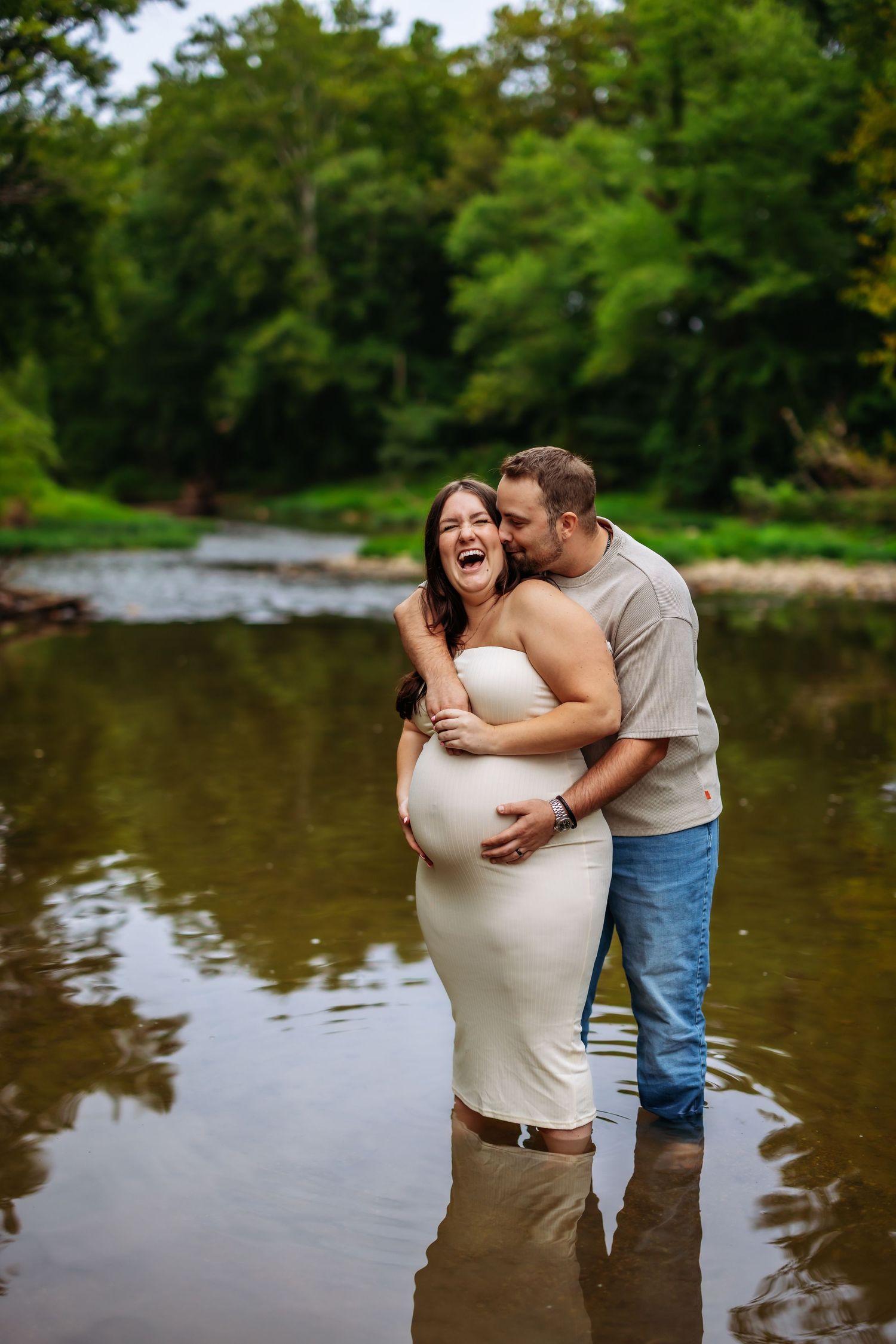 A couple shares tender moments by a serene lake surrounded by lush greenery during a photo session.