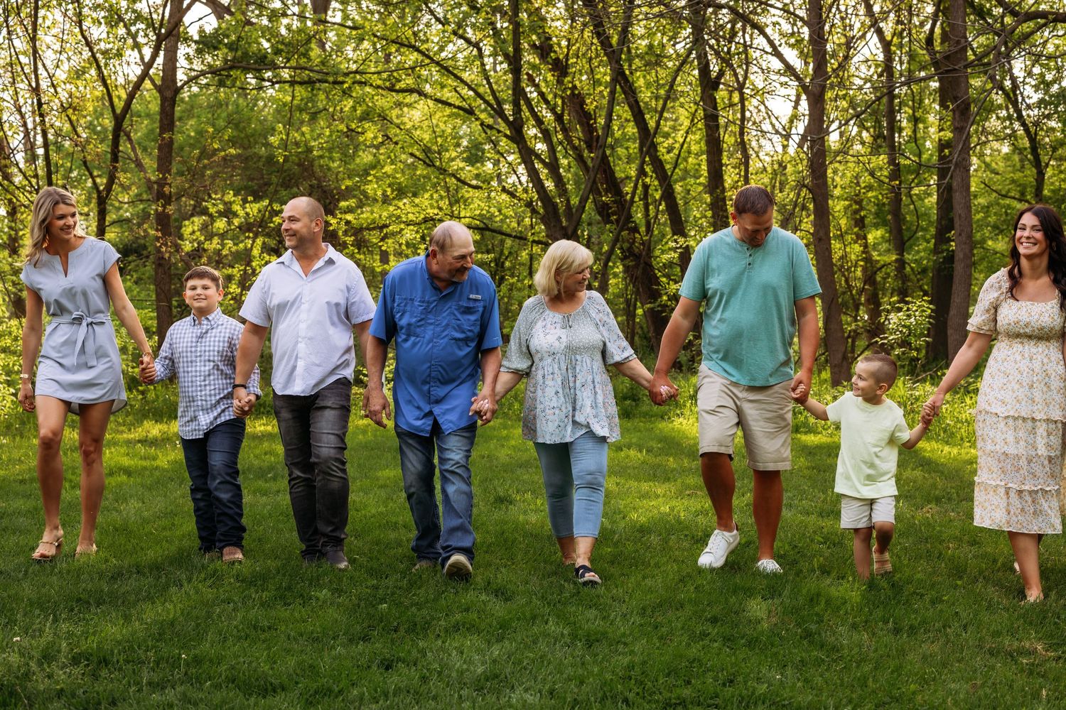 Multi-generational family walking together in a line through a green summer garden.