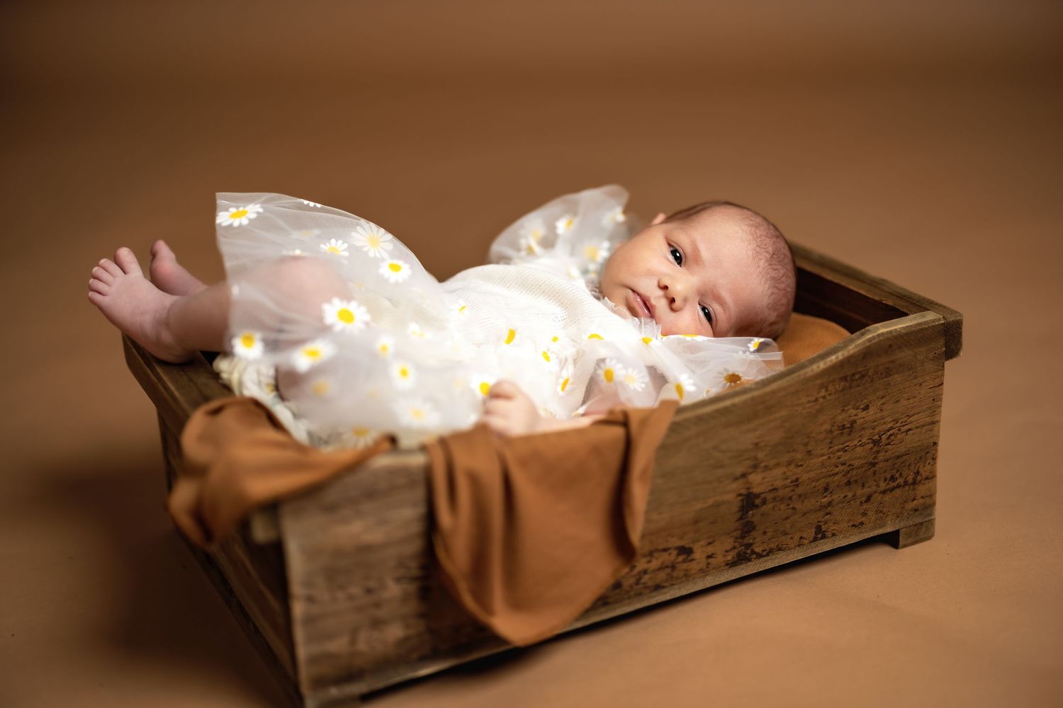 Sleeping newborn baby in white outfit resting peacefully in rustic wooden box.