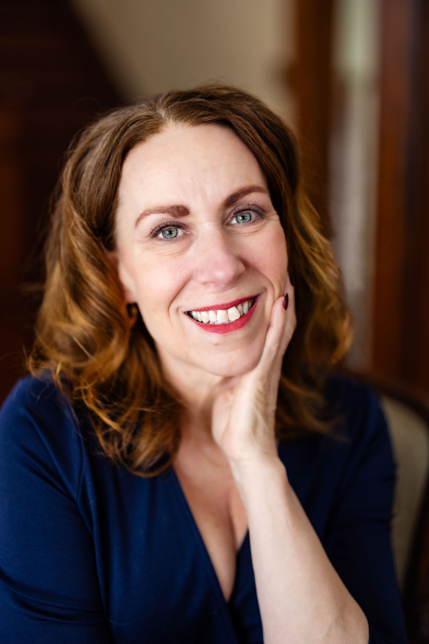 A series of five headshots showing someone in a navy blue top with brown hair smiling warmly at the camera.