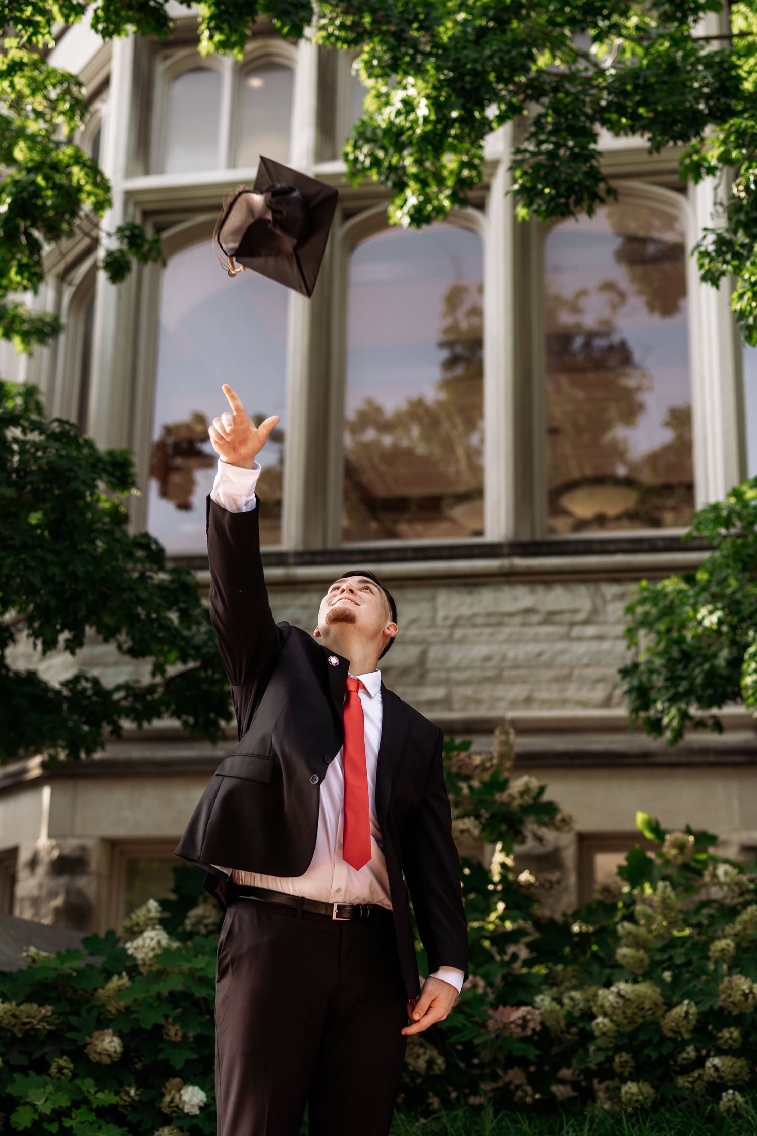 A person in a business suit and red tie gestures dramatically in a series of four outdoor photos near a building.