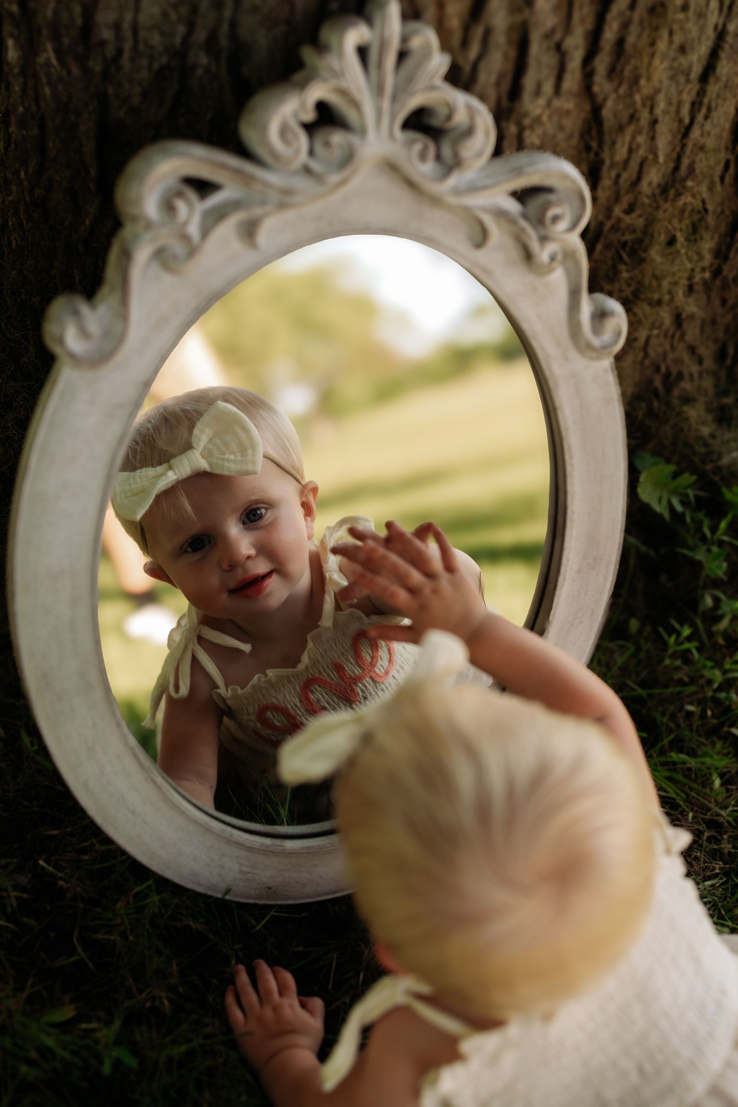 A series of mirror reflections showing a small child in white clothing interacting with their own reflection.