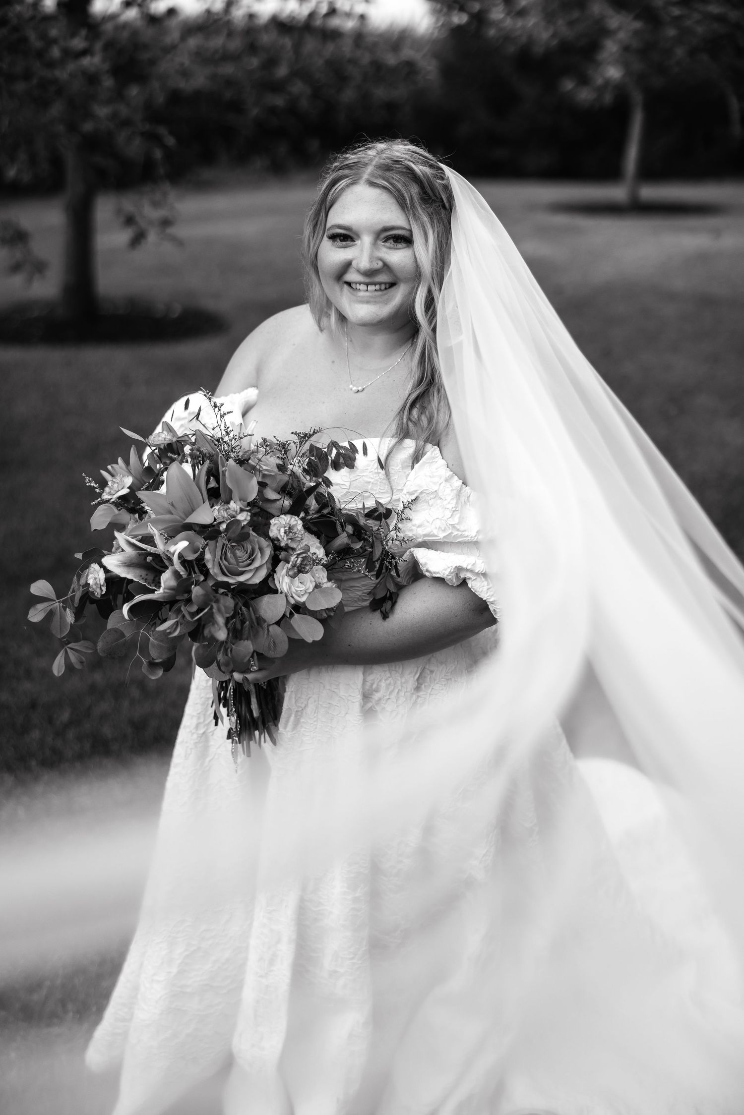 A series of black and white bridal portraits showcase an elegant wedding veil and bouquet in an outdoor garden setting.
