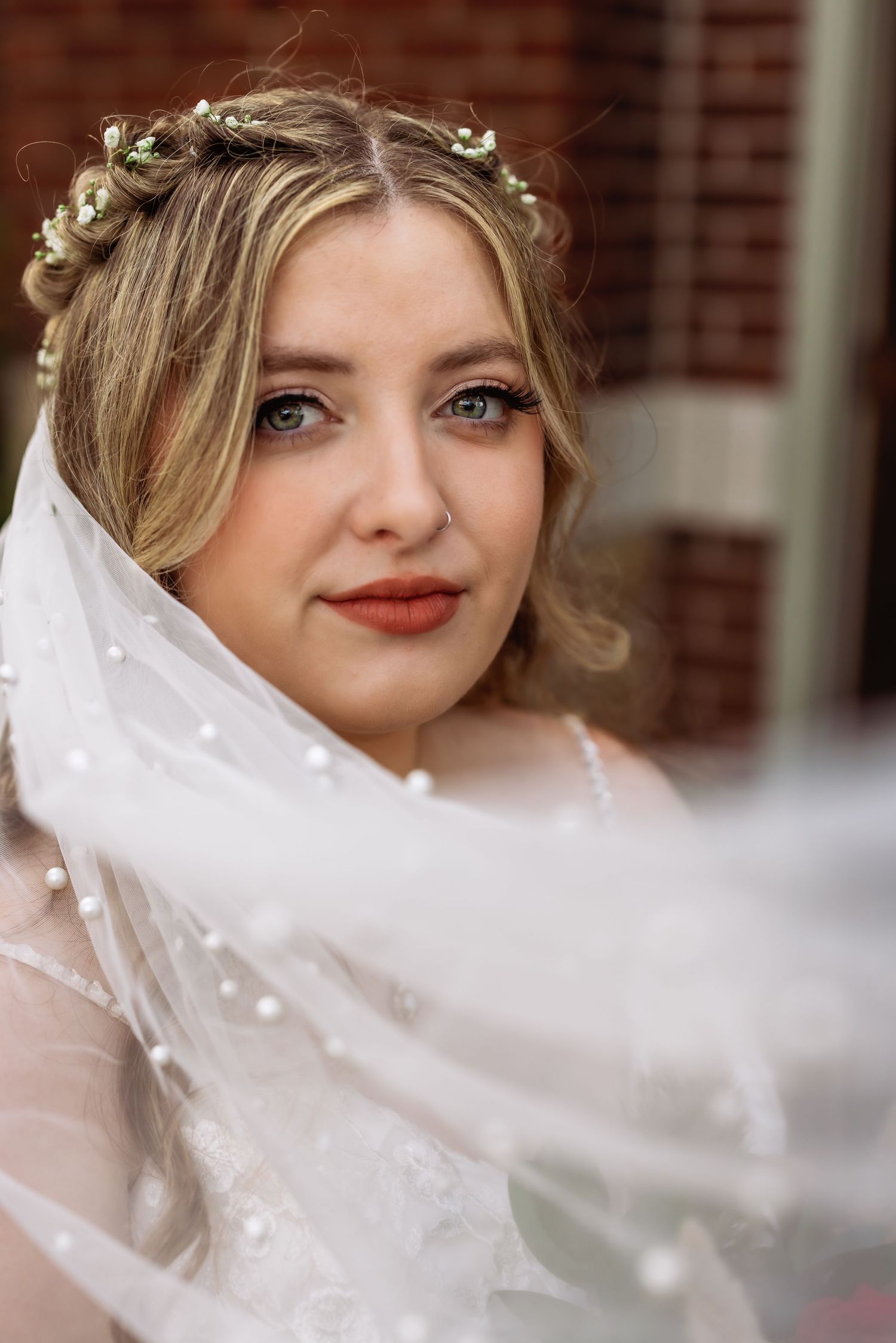 A close-up bridal portrait with delicate floral crown and flowing veil.