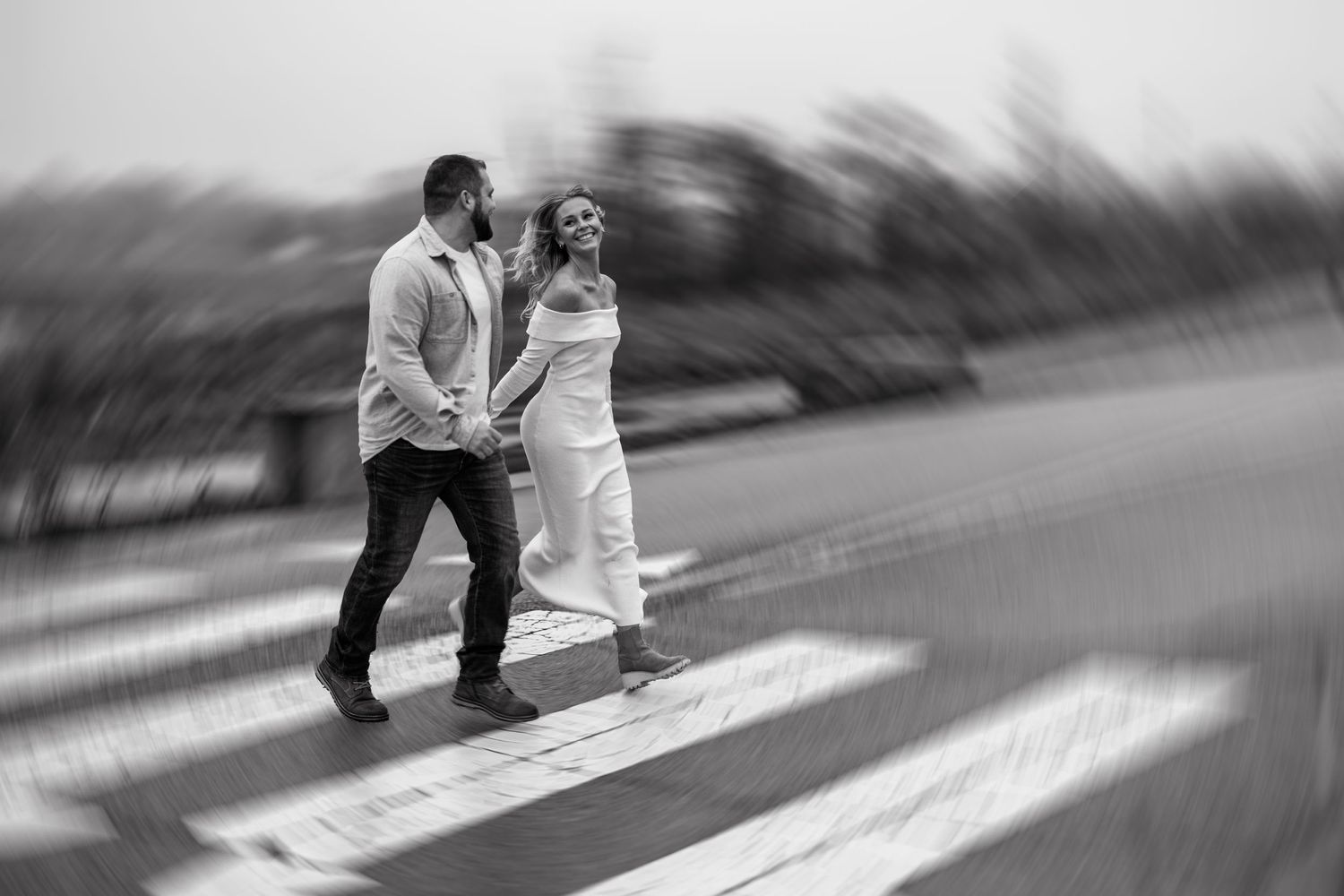 A black and white motion blur photo of a couple walking together on a path.