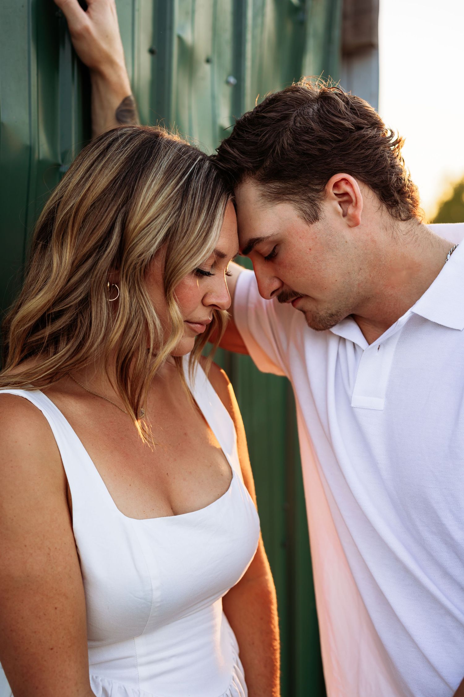 An intimate moment between two people in white clothing against a green backdrop.