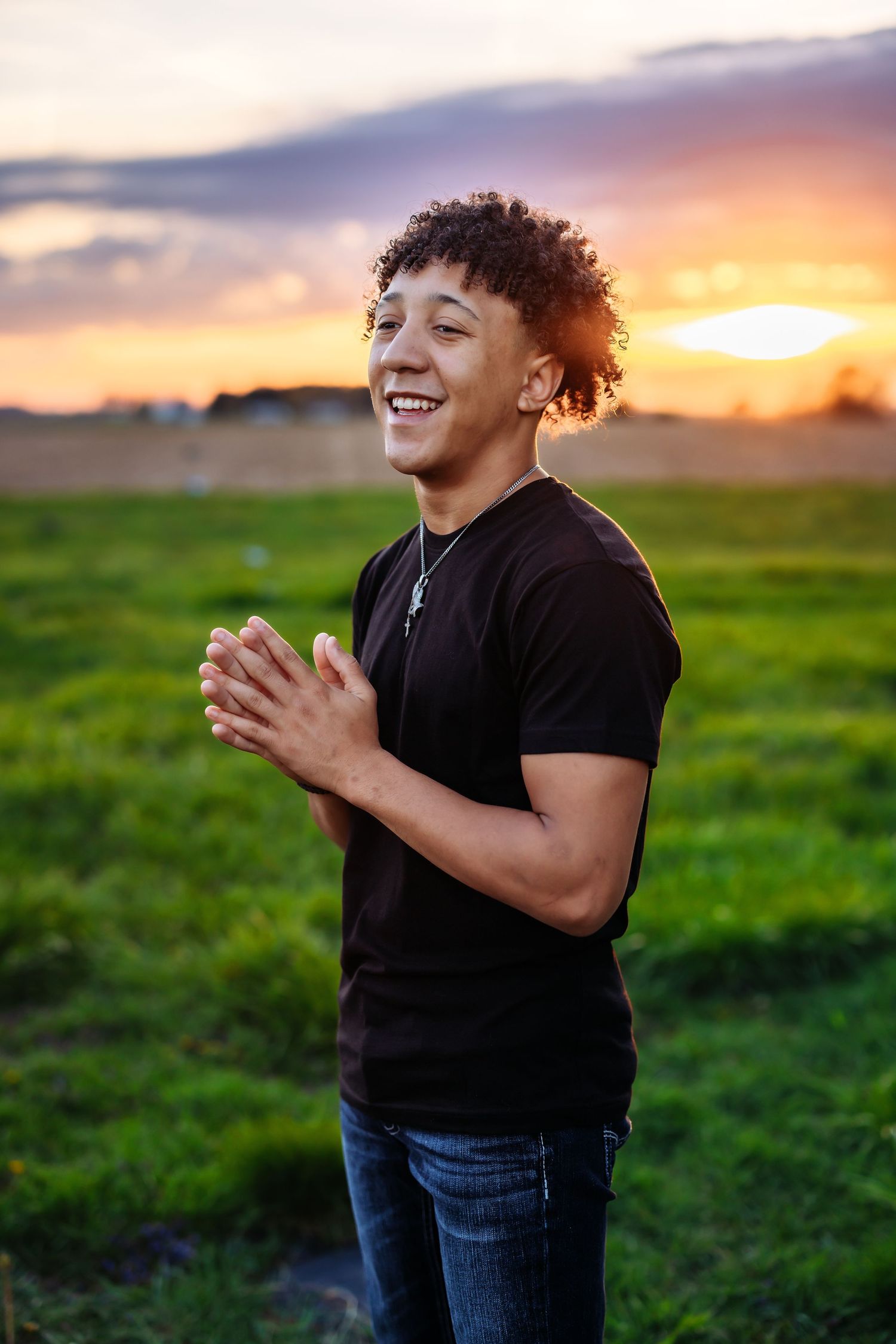 Person laughing joyfully in a field during golden sunset.