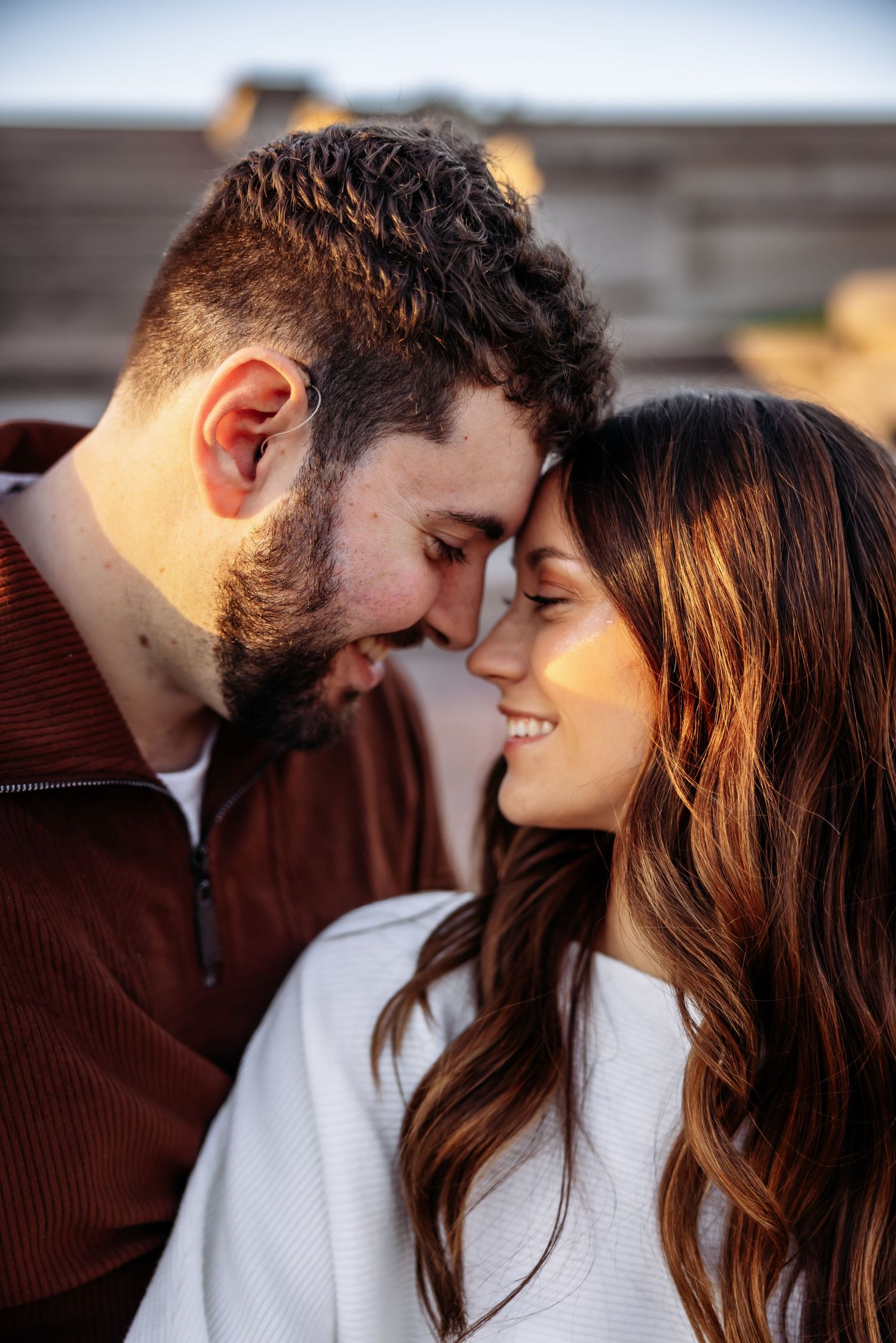 A romantic couple sharing an intimate moment outdoors, with soft lighting and warm expressions.