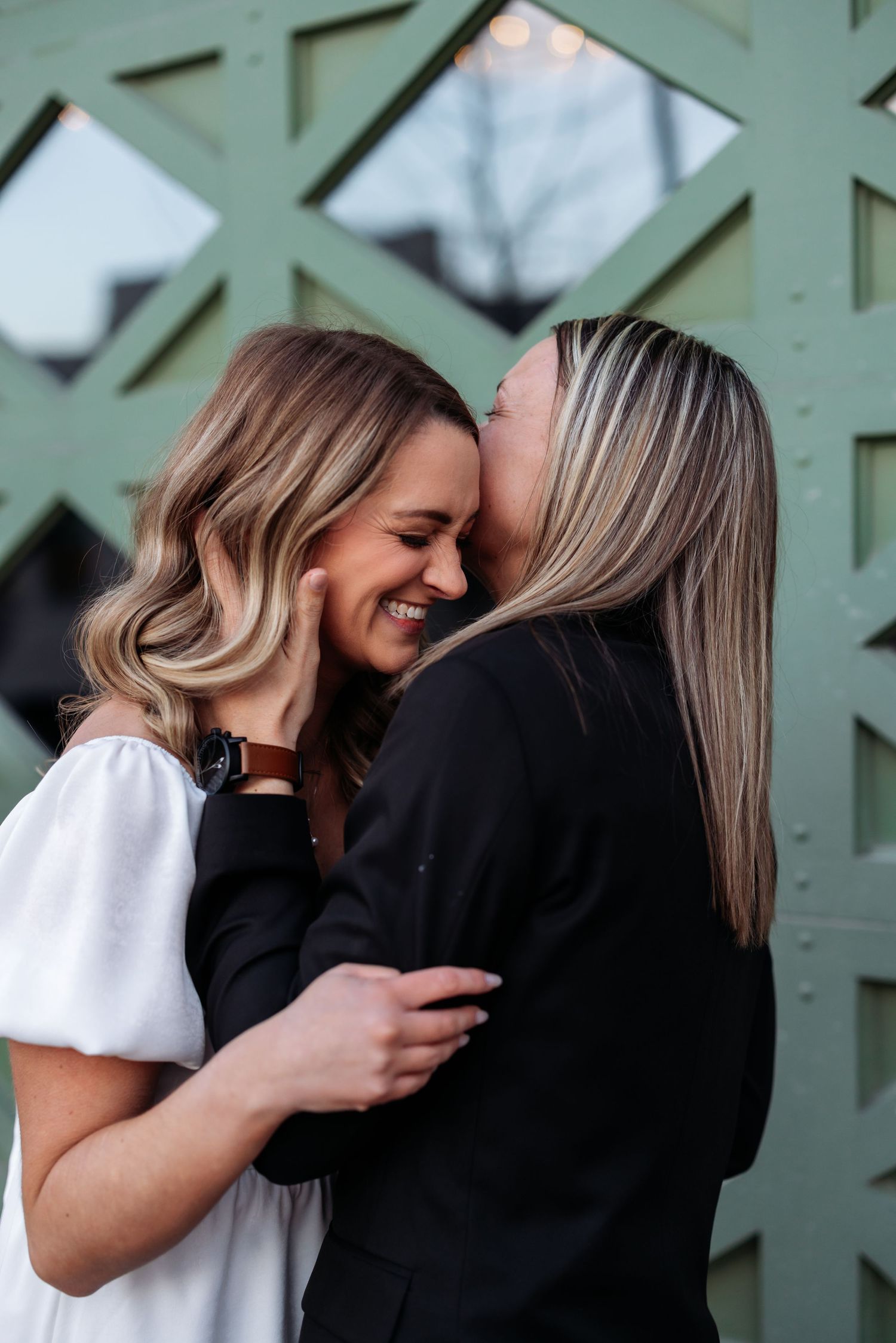 Intimate moment shared between two people against geometric patterned wall background.