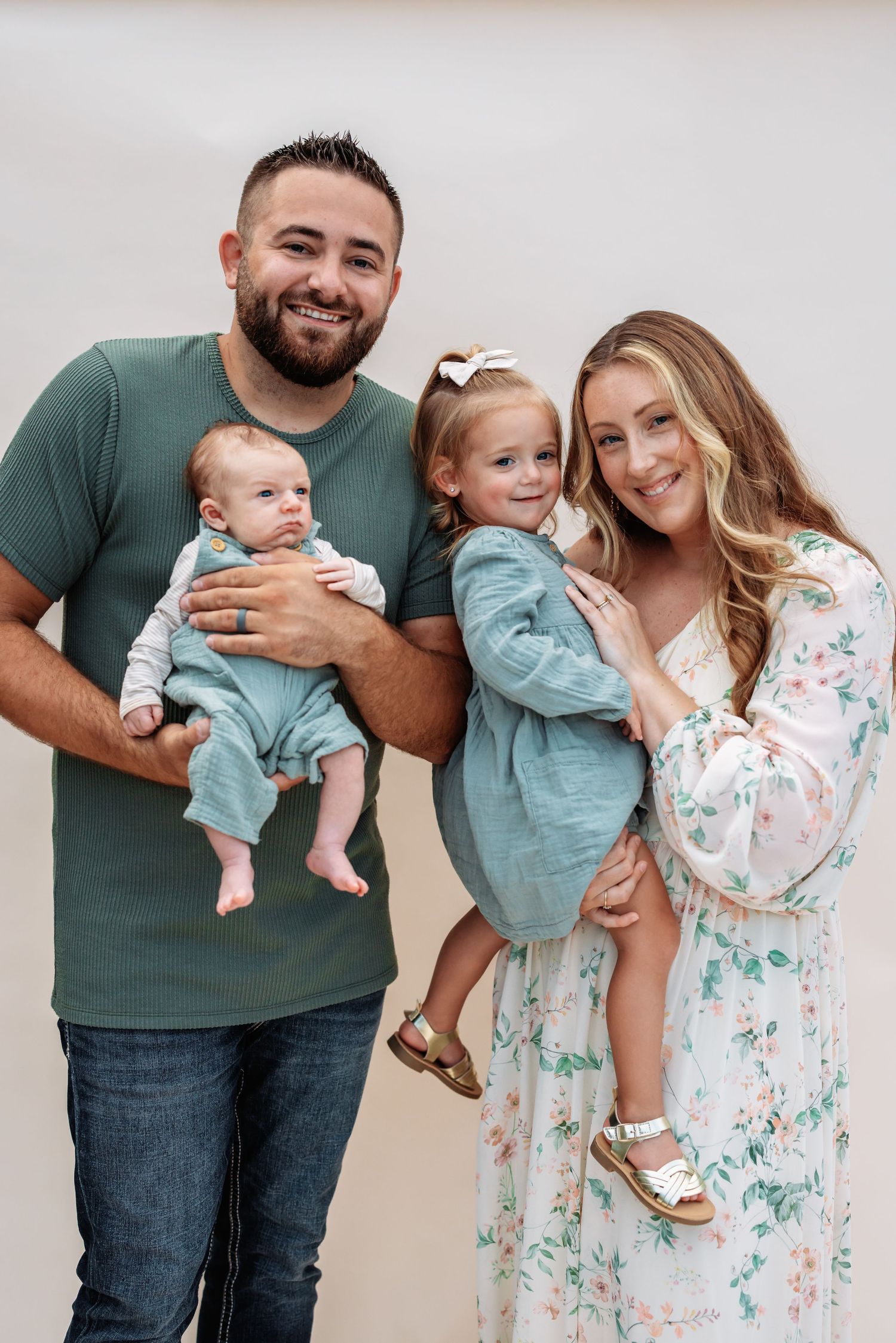Family portrait with parents and two children wearing coordinated blue and floral outfits.