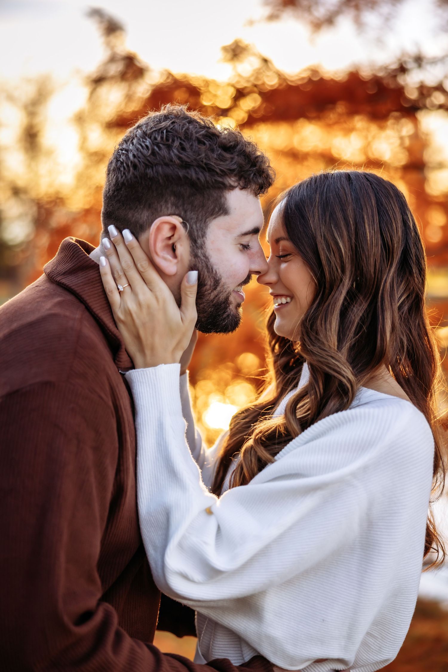 Romantic couple sharing intimate moments at sunset with warm golden light glowing behind them.