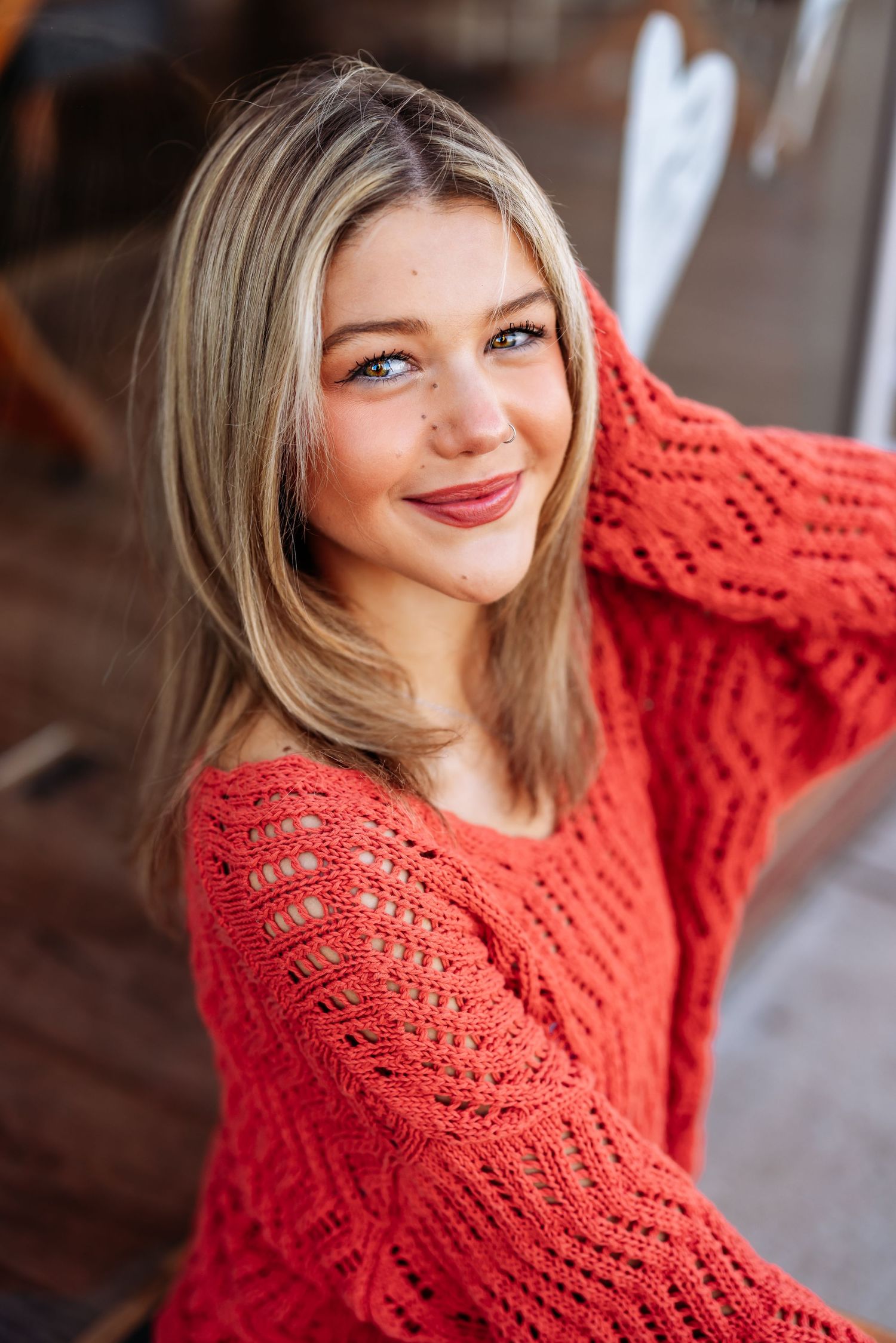 Woman in bright red knit sweater smiles warmly during casual portrait session.