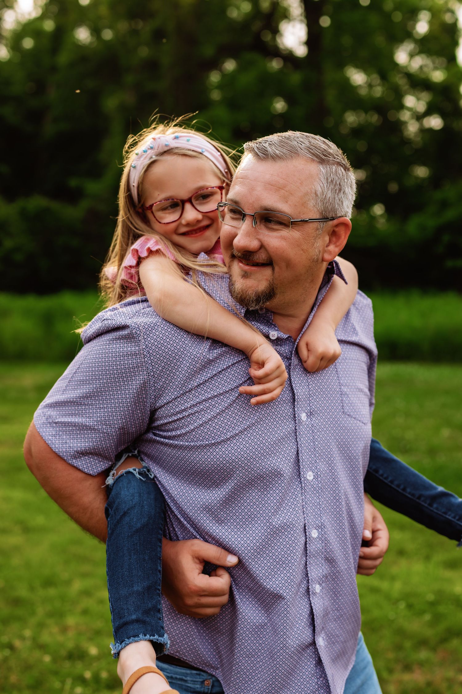 A playful piggyback ride moment captured outdoors on a sunny day in a grassy area.