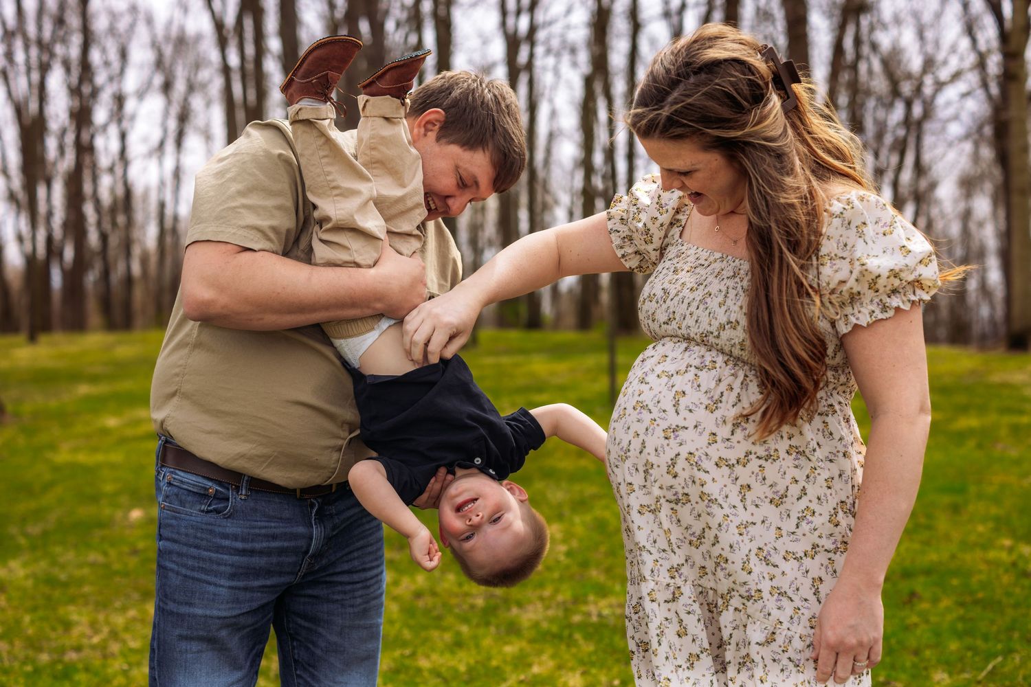 Intimate outdoor family photoshoot in a grassy field during spring with casual khaki and floral dress attire.