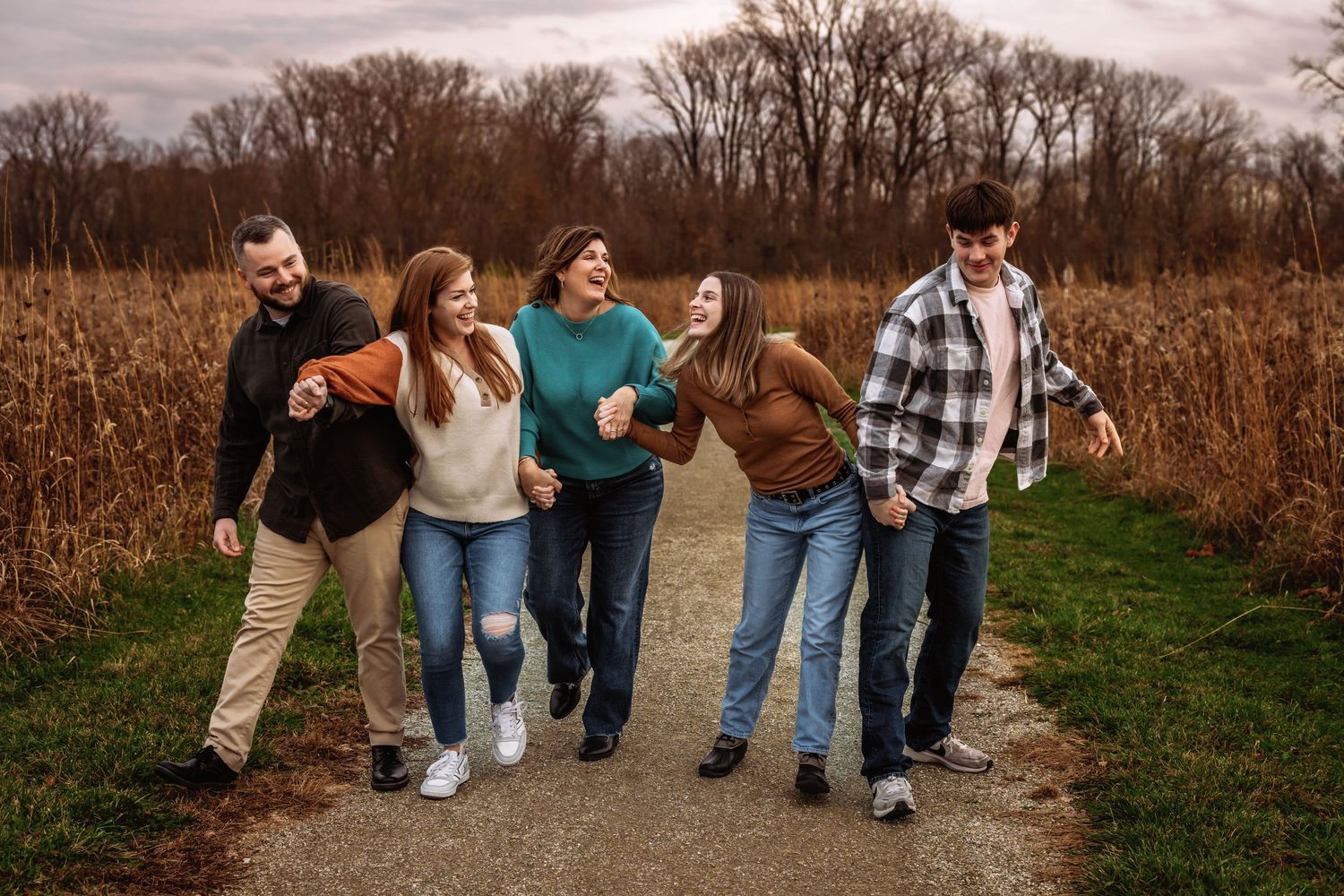 Group walking and laughing together on path through autumn cornfield.