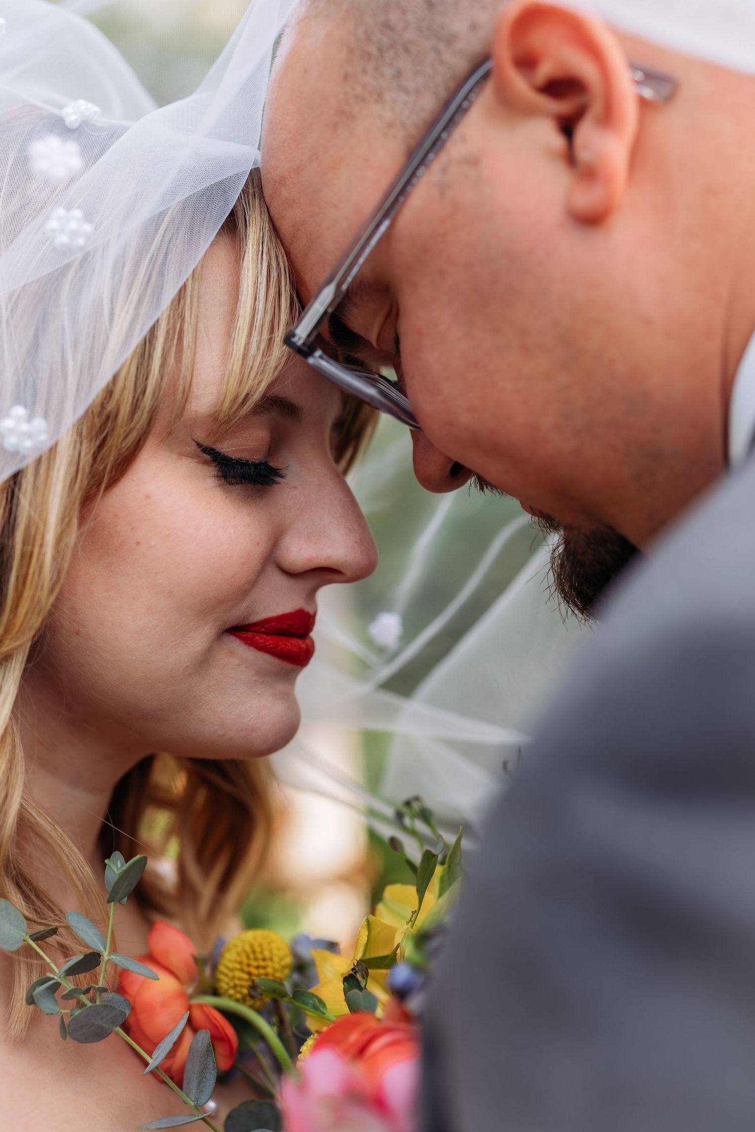 An intimate close-up wedding portrait featuring romantic details and colorful flowers.