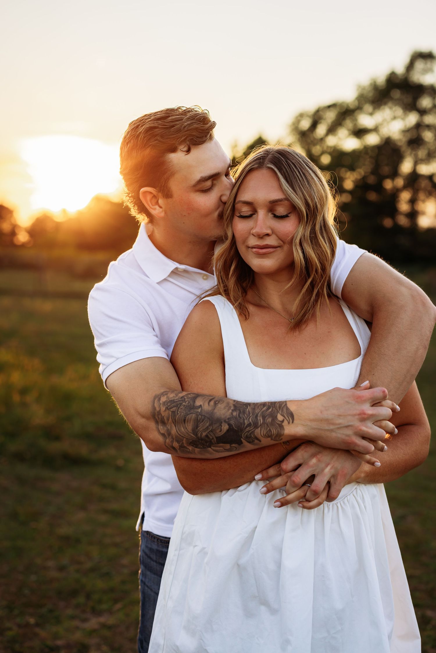 A romantic sunset embrace between two people in white clothing against a golden sky.