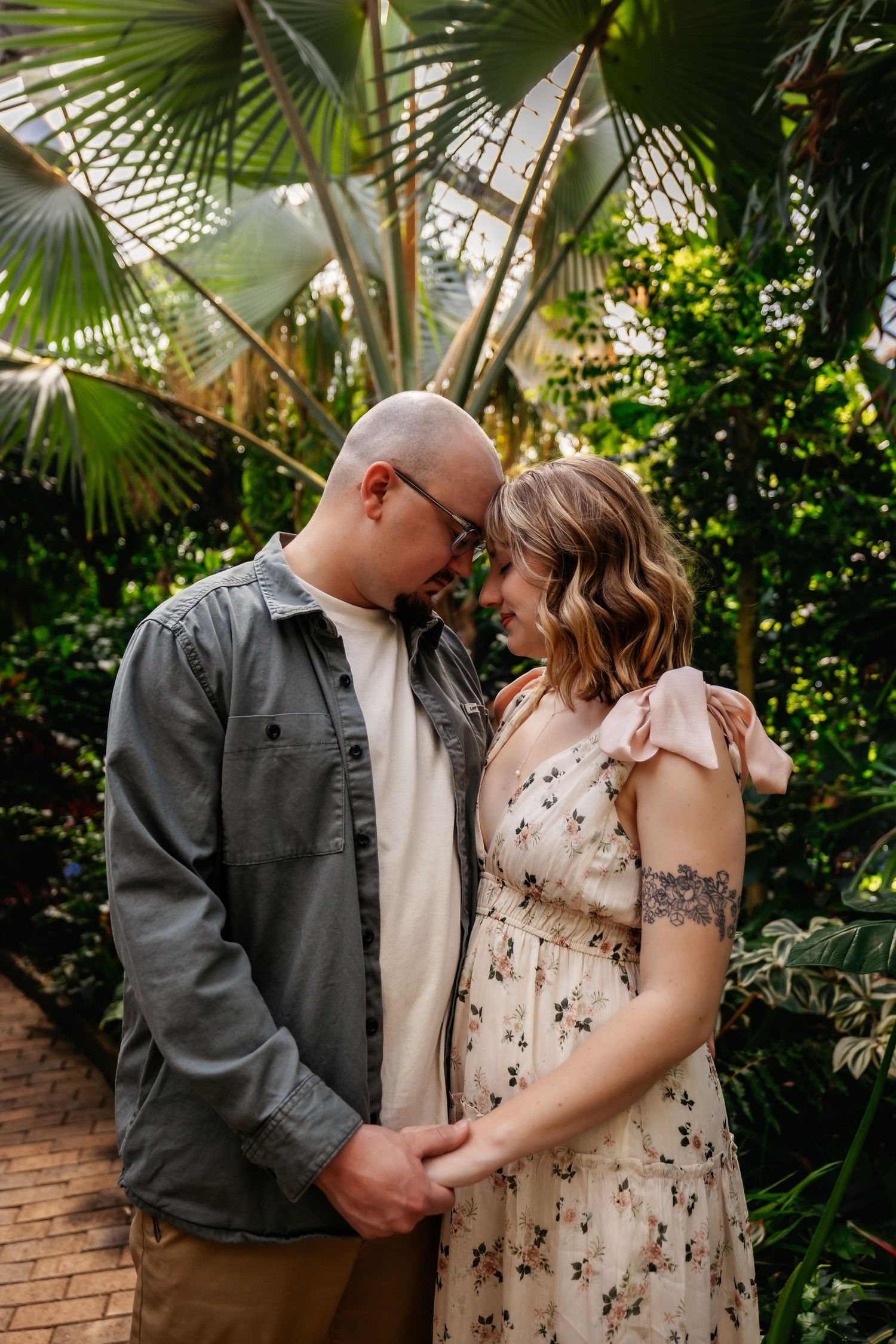 Couple sharing intimate moment under tropical palm trees in botanical garden setting.