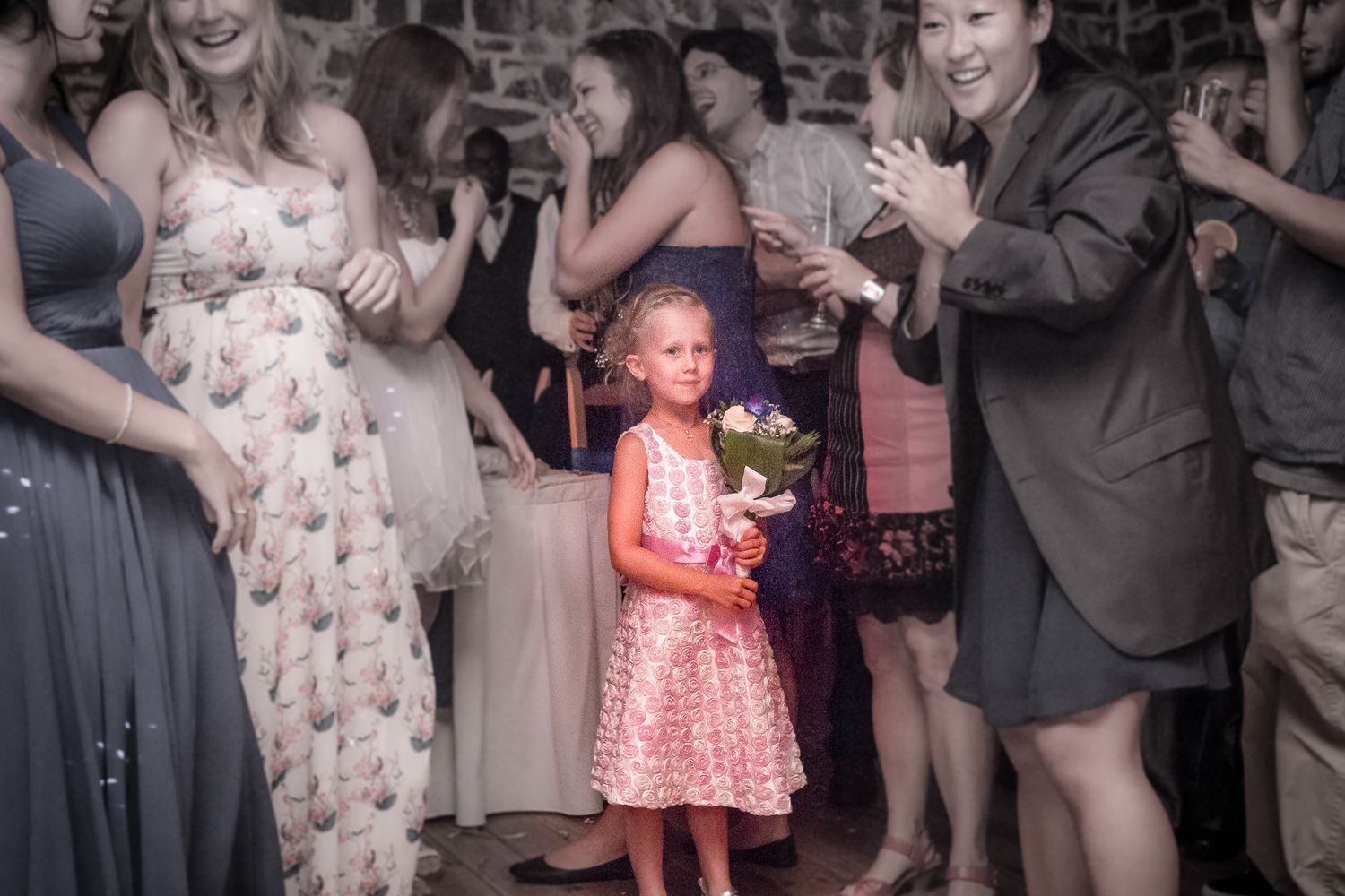 Photographie de mariage par Mathieu Breton : petite fille tenant un bouquet au milieu des invités.